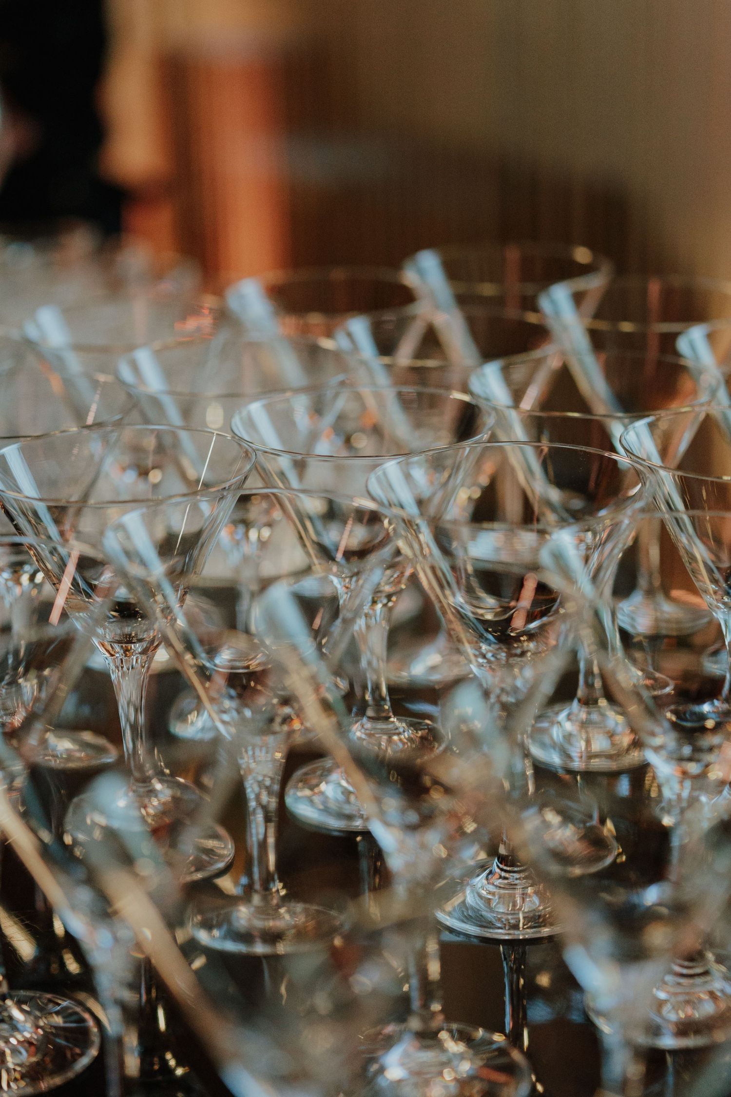 Close-up of multiple elegant empty martini glasses arranged on a table at an event.