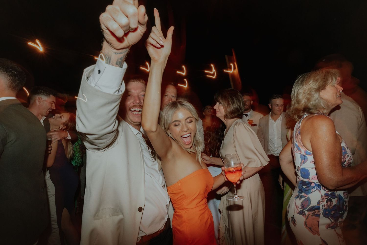Guests dancing and celebrating at lively outdoor wedding reception at night.