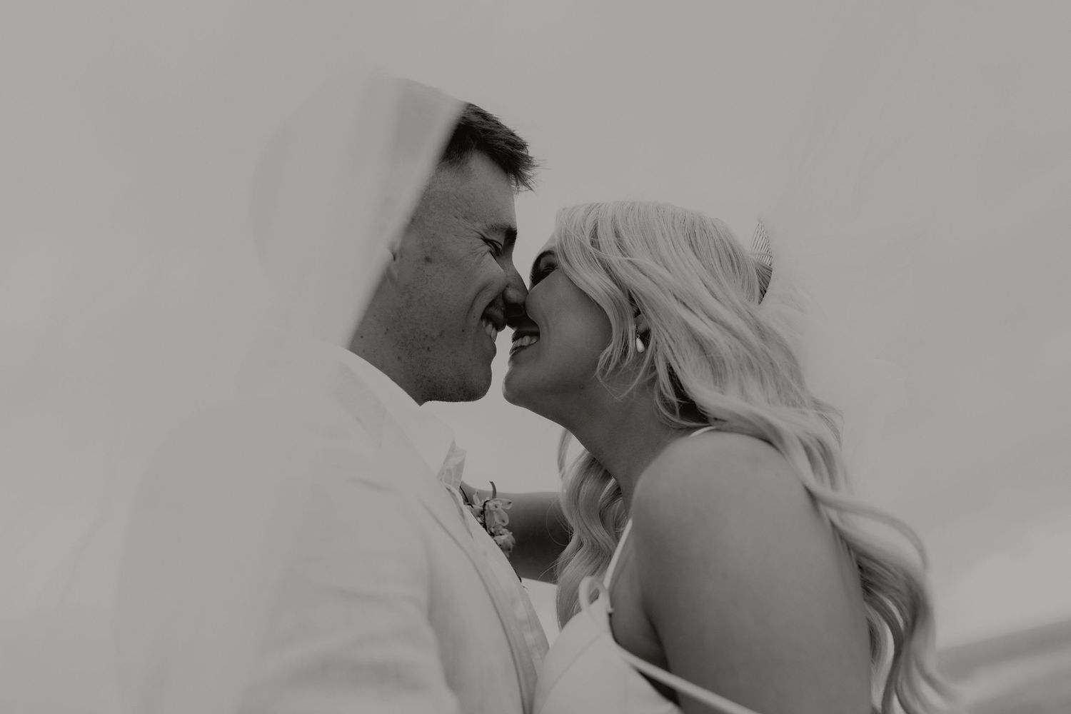 Black and white close-up of bride and groom sharing an intimate moment, nearly kissing.