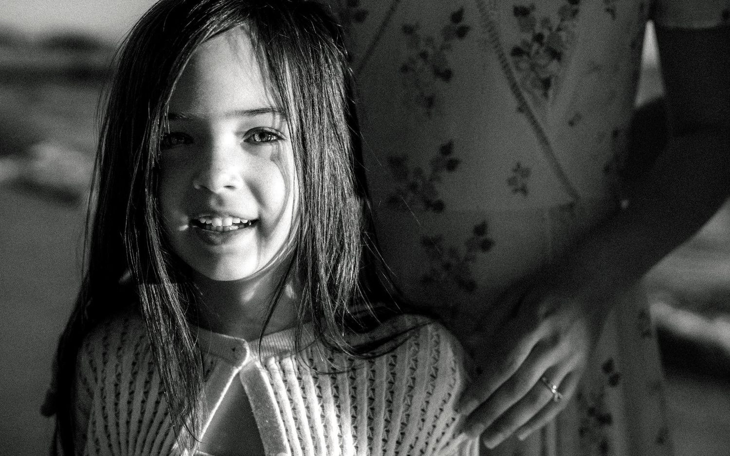 Black and white portrait of smiling young girl with long hair at the beach.
