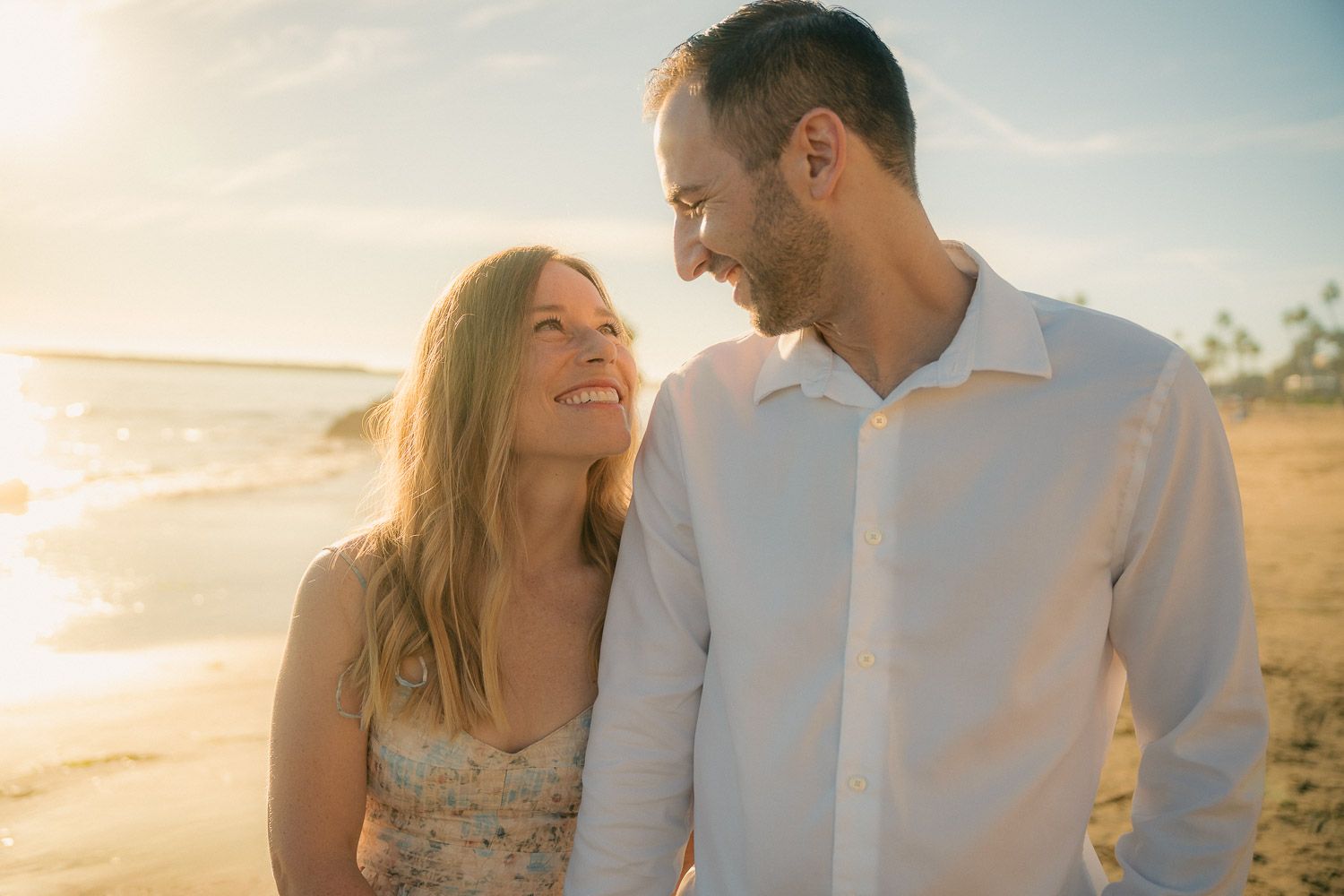 Happy couple smiling at each other on a sunny tropical beach.