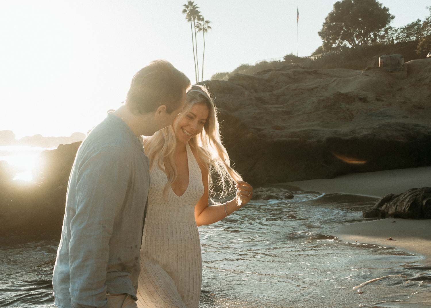 Romantic couple sharing a tender moment on a sunlit sandy beach.
