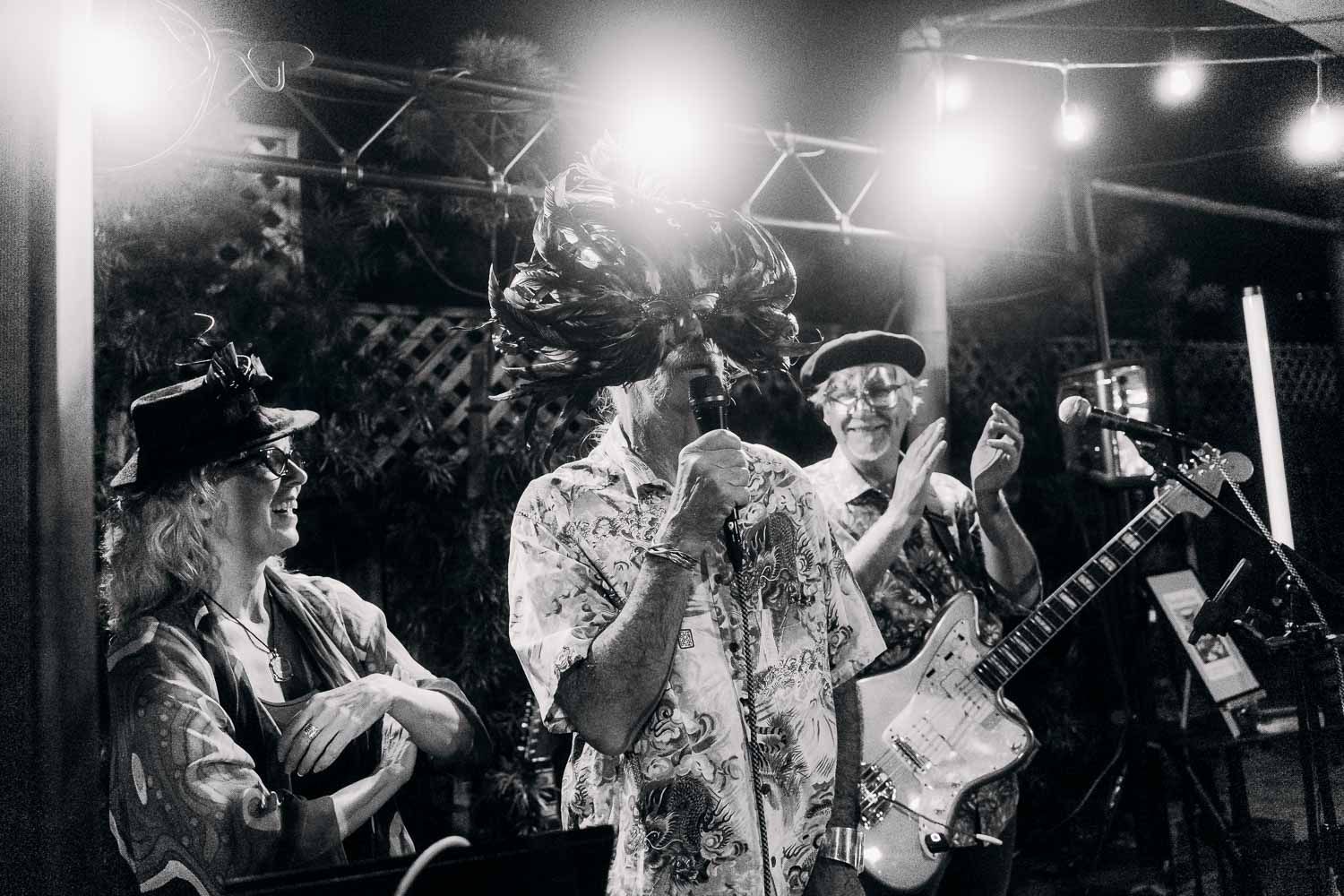 Black and white photo of a live band performing outdoors at night under string lights.
