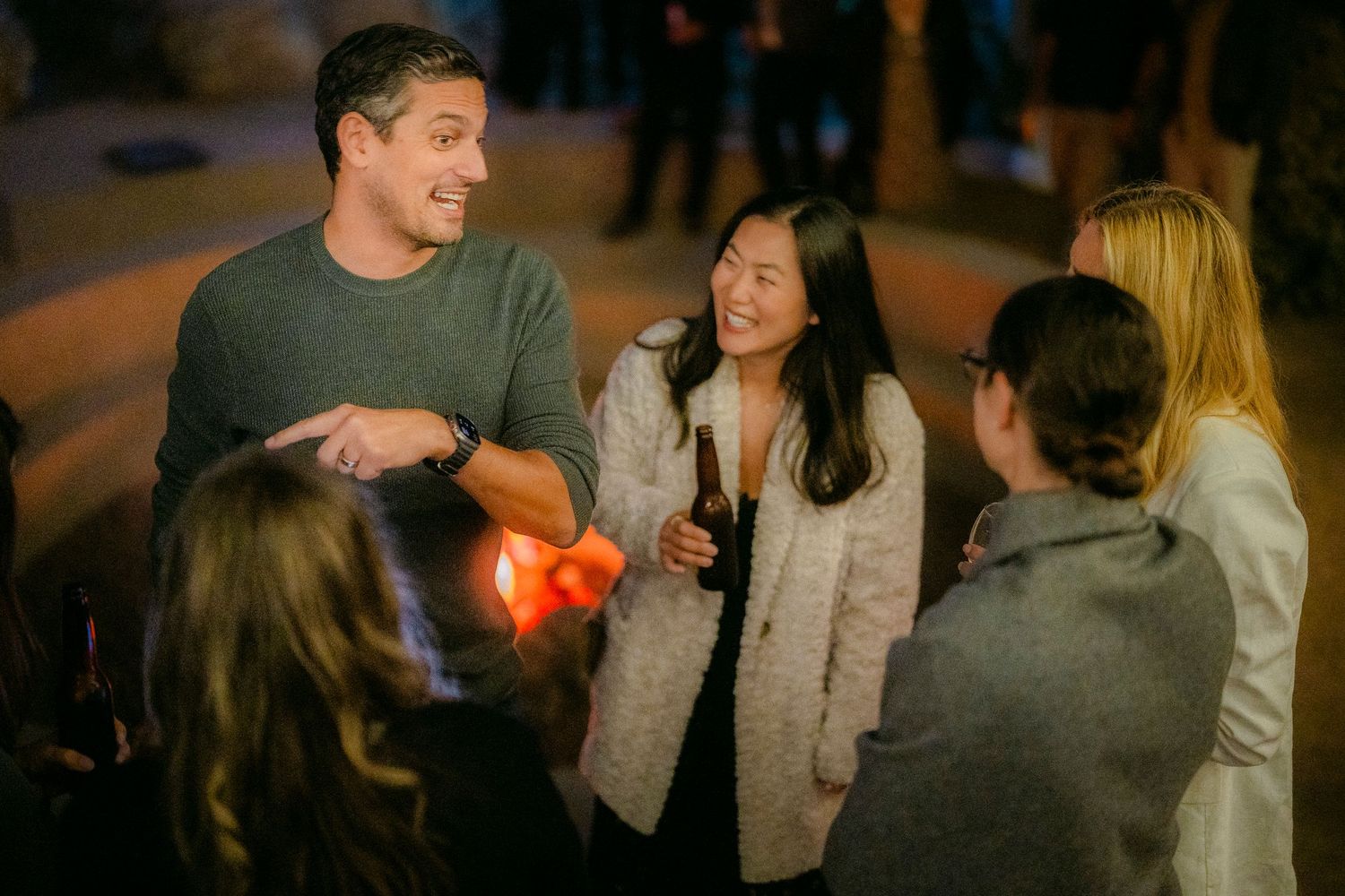 Group of guests engaged in lively conversation at an outdoor nighttime social gathering.