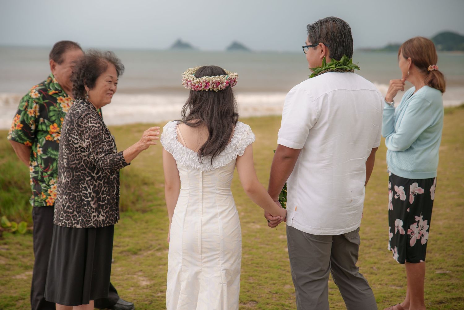 Newlyweds walking with family on a Hawaii beach after their ceremony