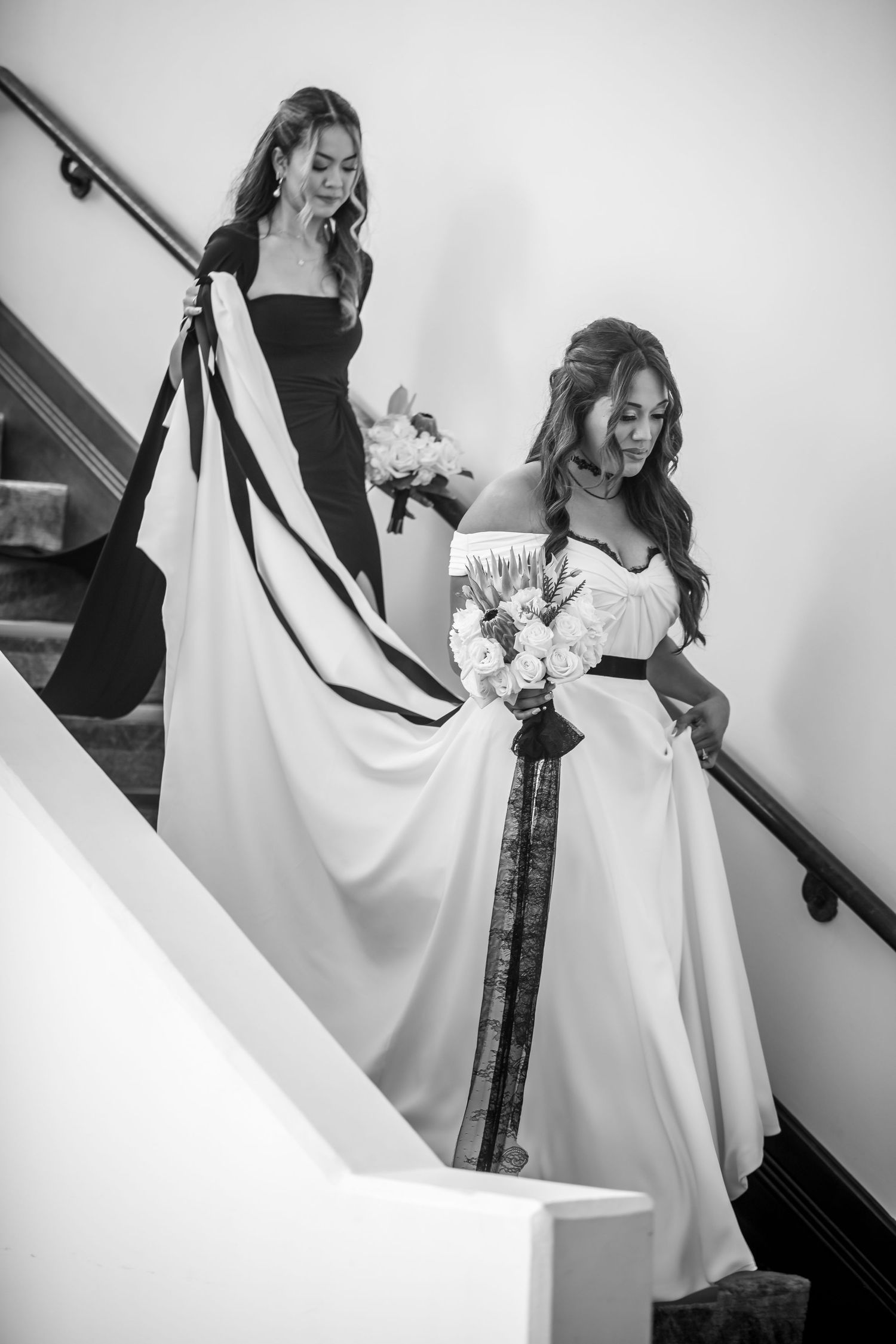 Bride and flower girl walking down a staircase in a black-and-white wedding moment