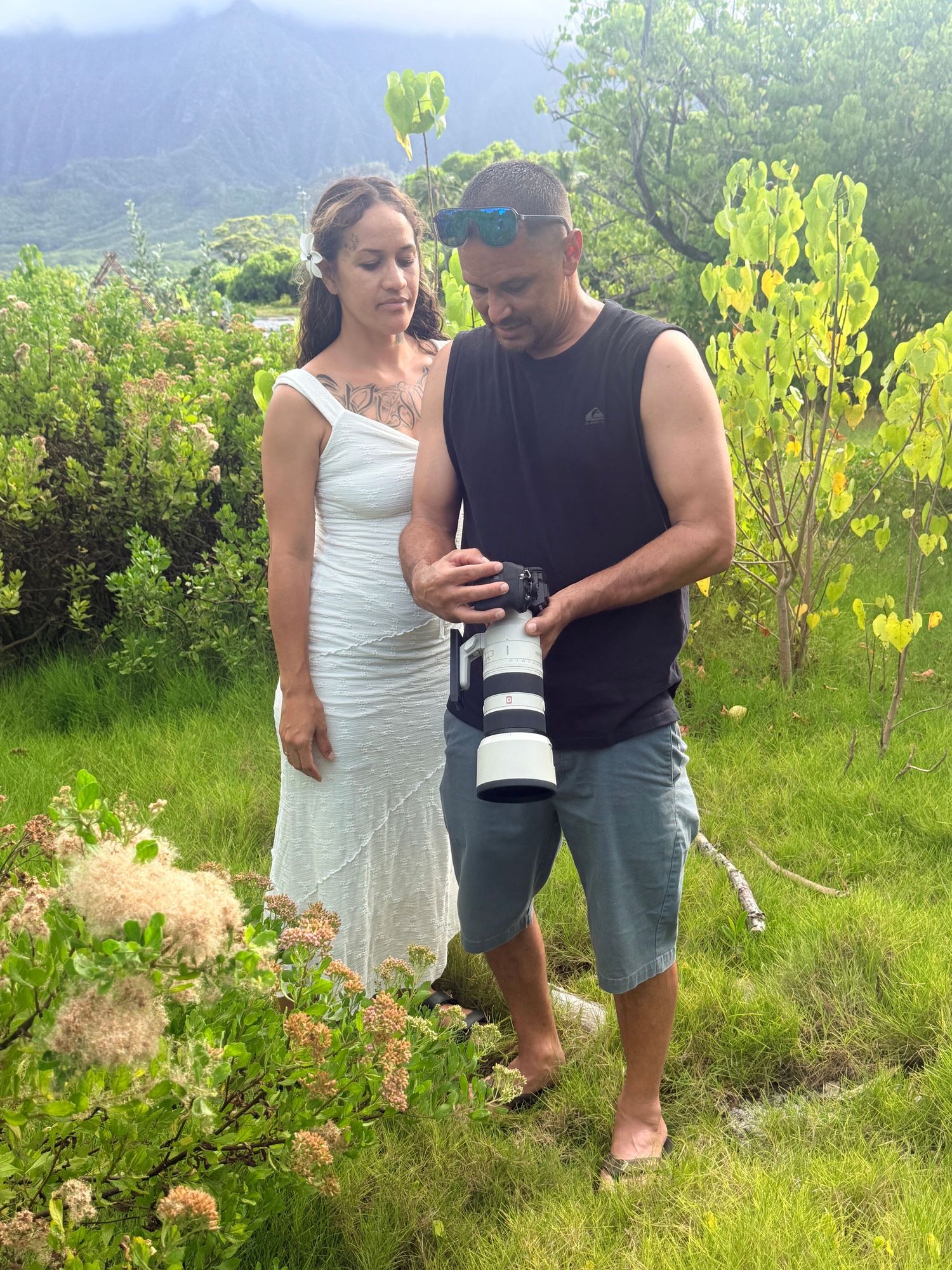 Joseph reviewing a photograph on his camera while Bobbie-Rose stands beside him outdoors