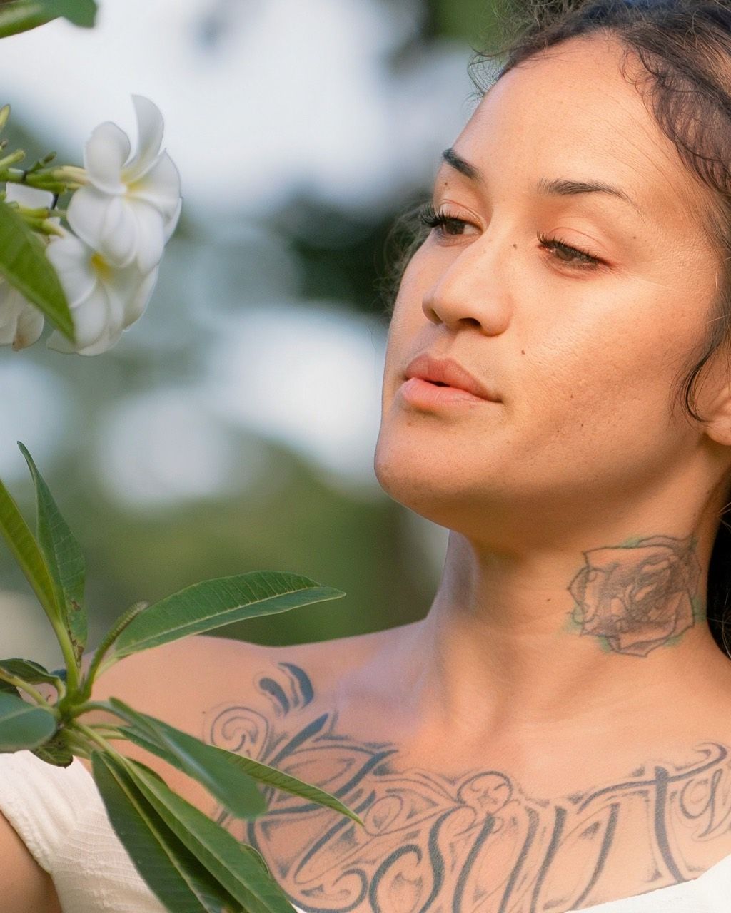 Bobbie-Rose pausing beside plumeria blossoms in soft evening light