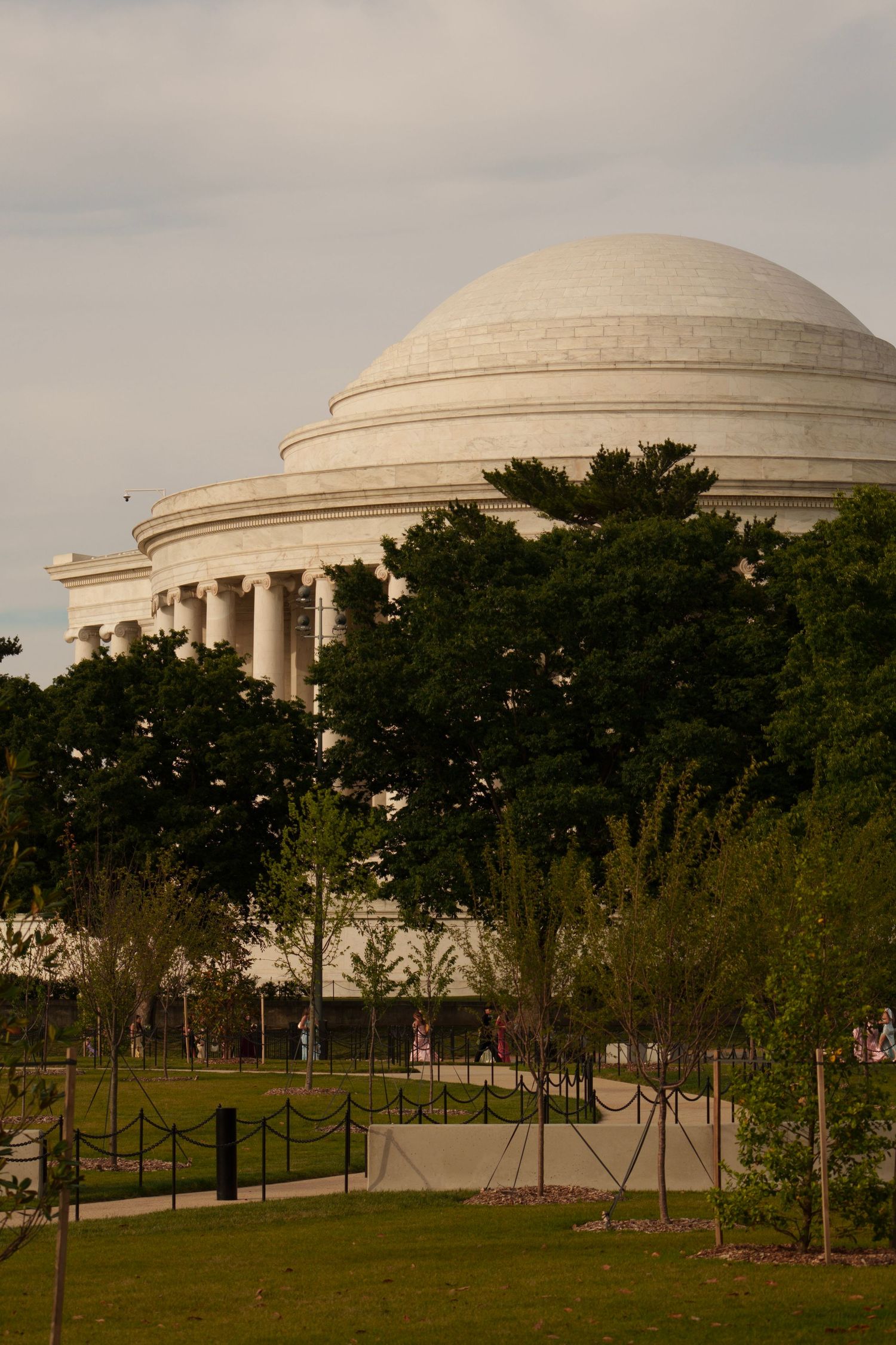The domed Jefferson Memorial rises above lush green trees on a cloudy day in Washington D.C.