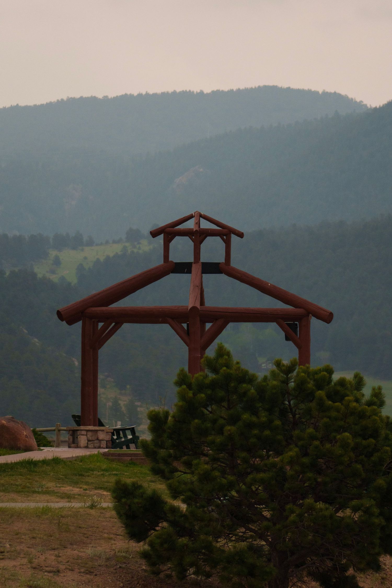 Rustic wooden timber frame pavilion structure with misty forested mountains in the background.