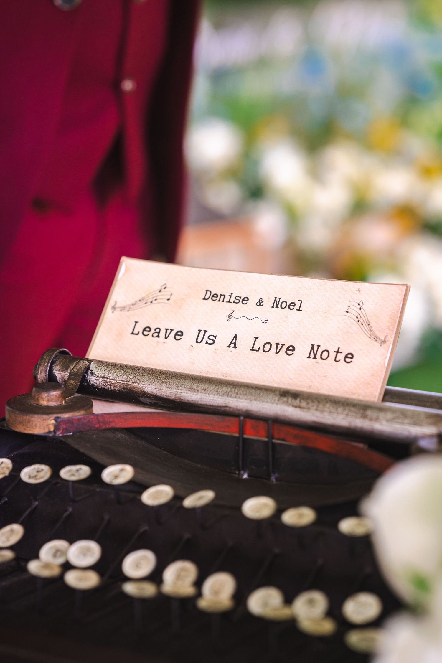 Vintage typewriter with a romantic sign reading Denise & Noel Leave Us A Love Note at a wedding reception.