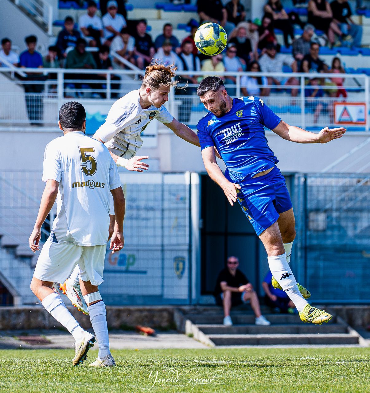 Joueur du Gap Foot 05 remportant un duel aérien lors d'un match, Hautes-Alpes, photographié par Yannick Eyraud
