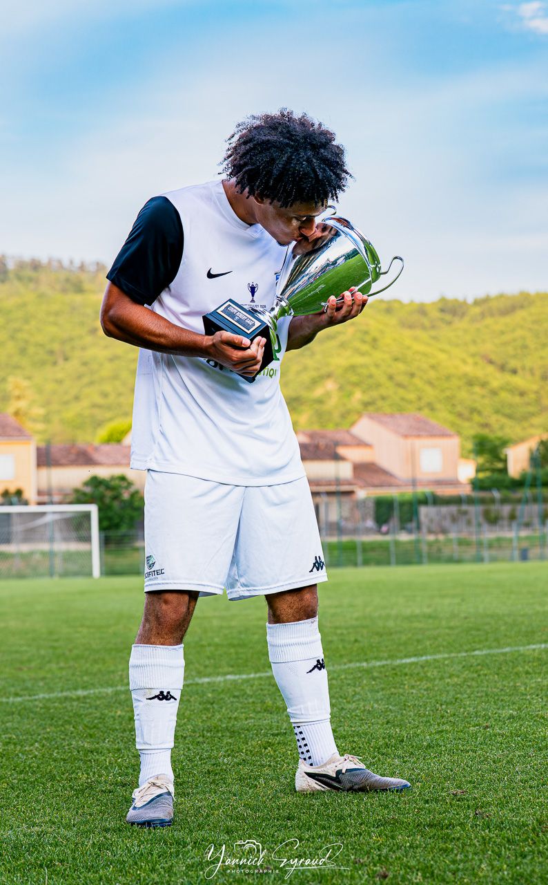 Joueur du Gap Foot 05 embrassant la coupe des alpes après la victoire en finale, photographié par Yannick Eyraud