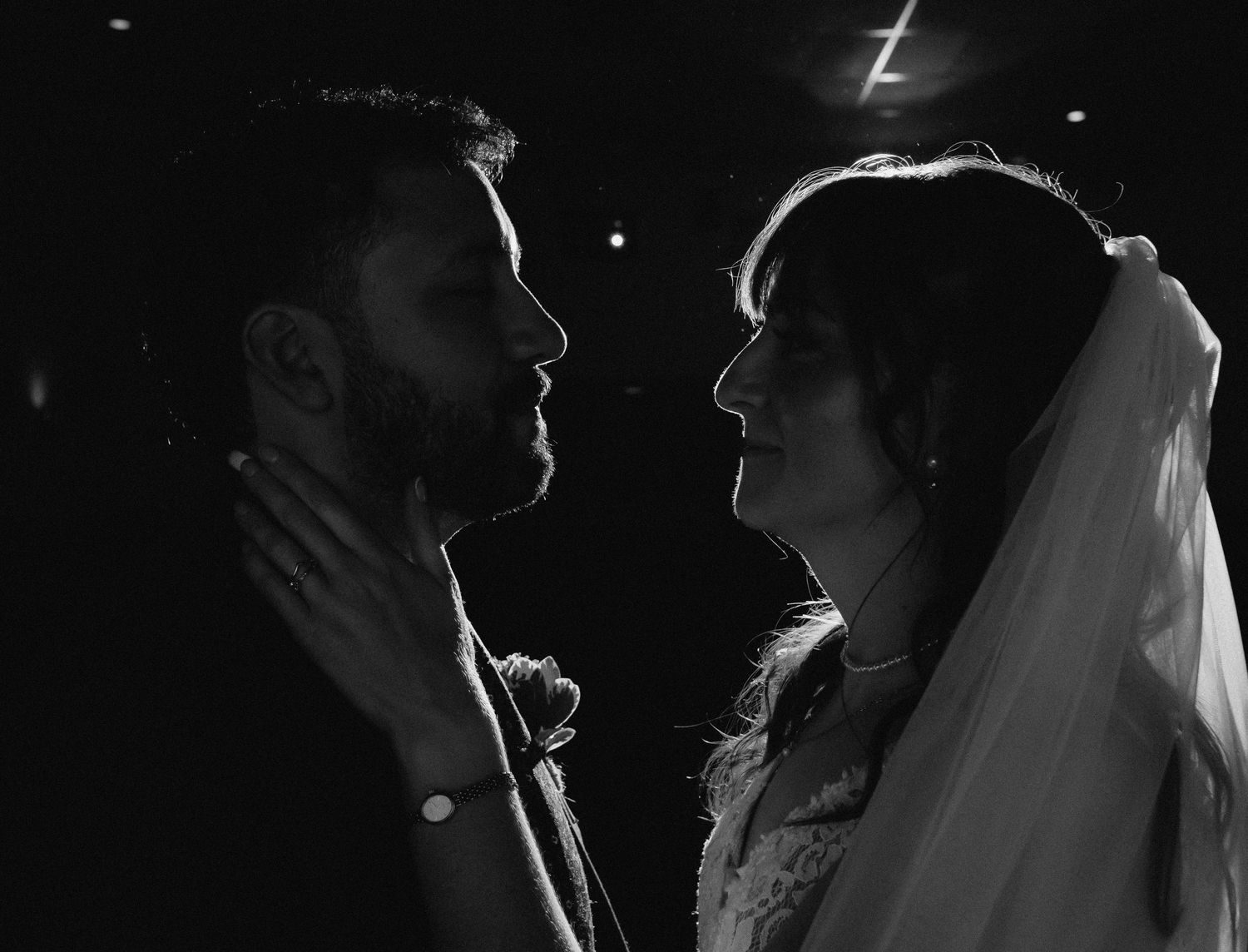 Black and white wedding photo of bride and groom sharing an intimate moment, faces close together.