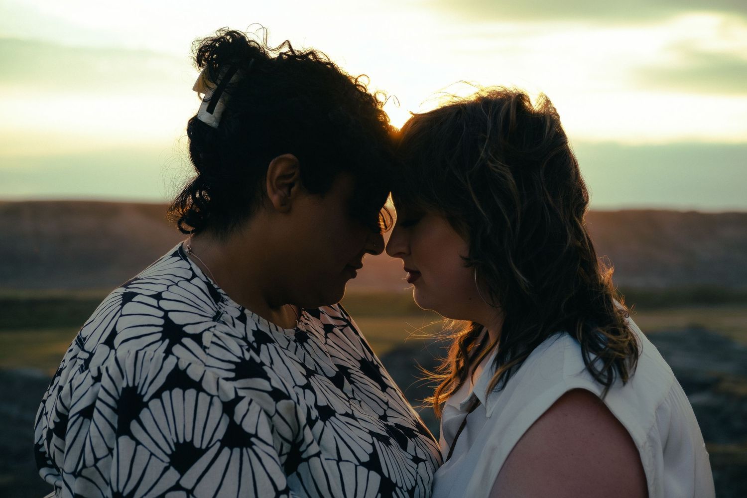 Couple sharing an intimate moment at sunset in a desert landscape, foreheads touching romantically.