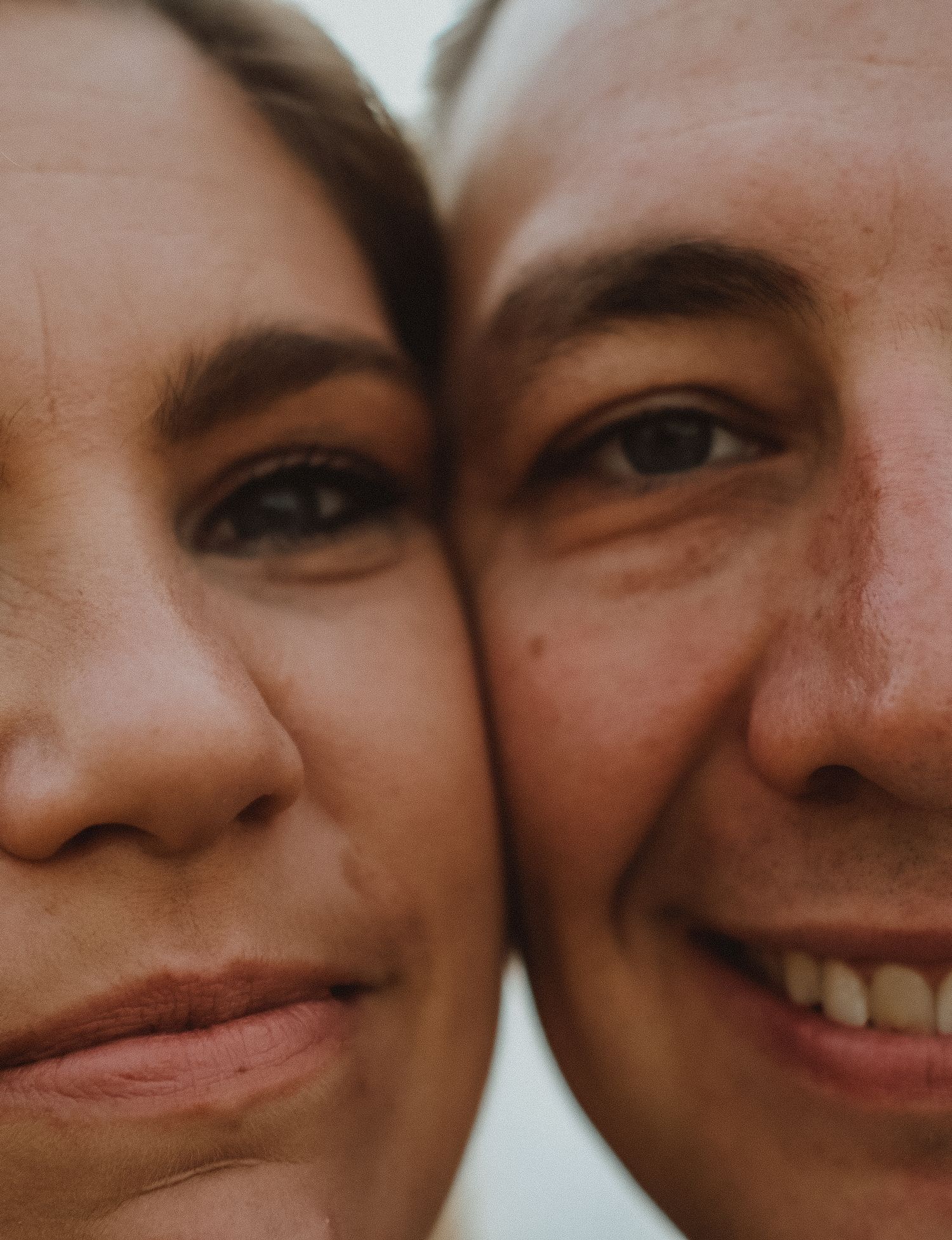 Intimate close-up portrait of a smiling couple with cheeks touching, showcasing natural skin texture.