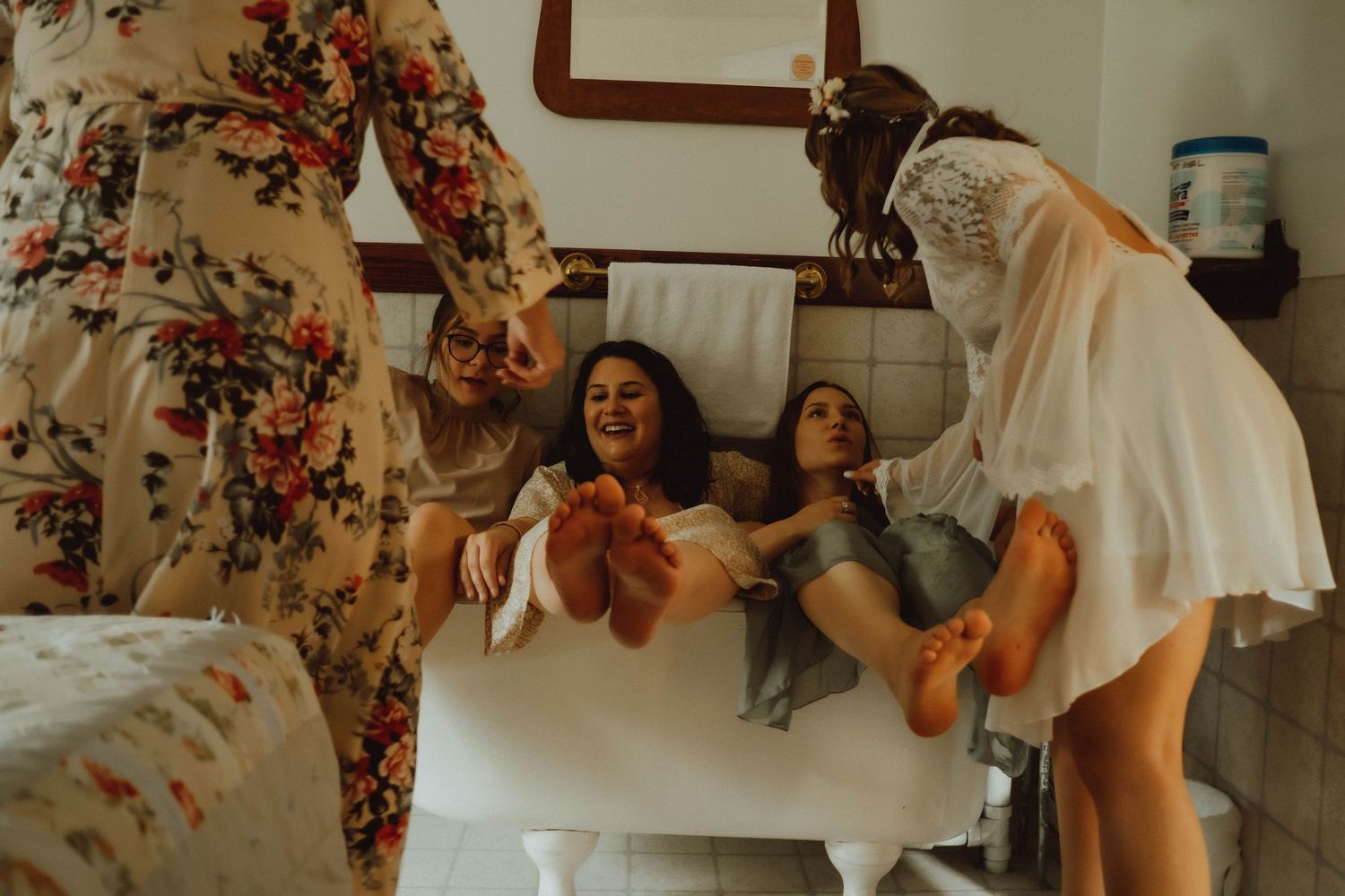 Joyful bridal party laughing together in a bathroom during wedding day preparations.