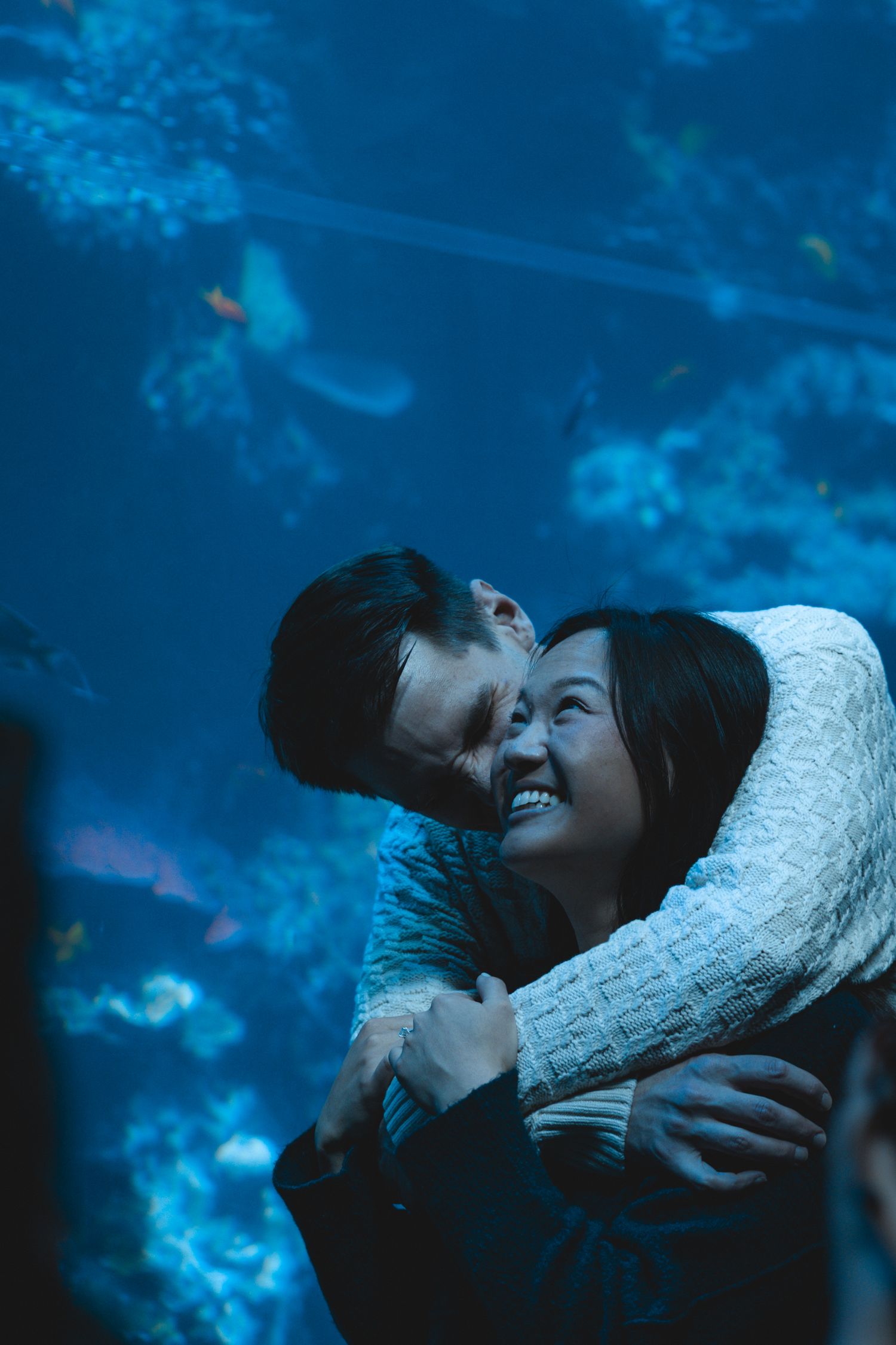 A romantic moment captured in blue tones with two people embracing in winter sweaters.