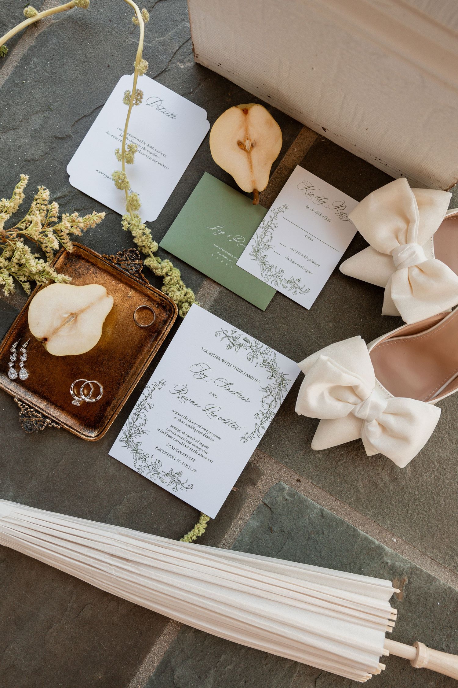 The image shows a collection of wedding stationery items, including an invitation, tags, and bows, arranged on a dark background.