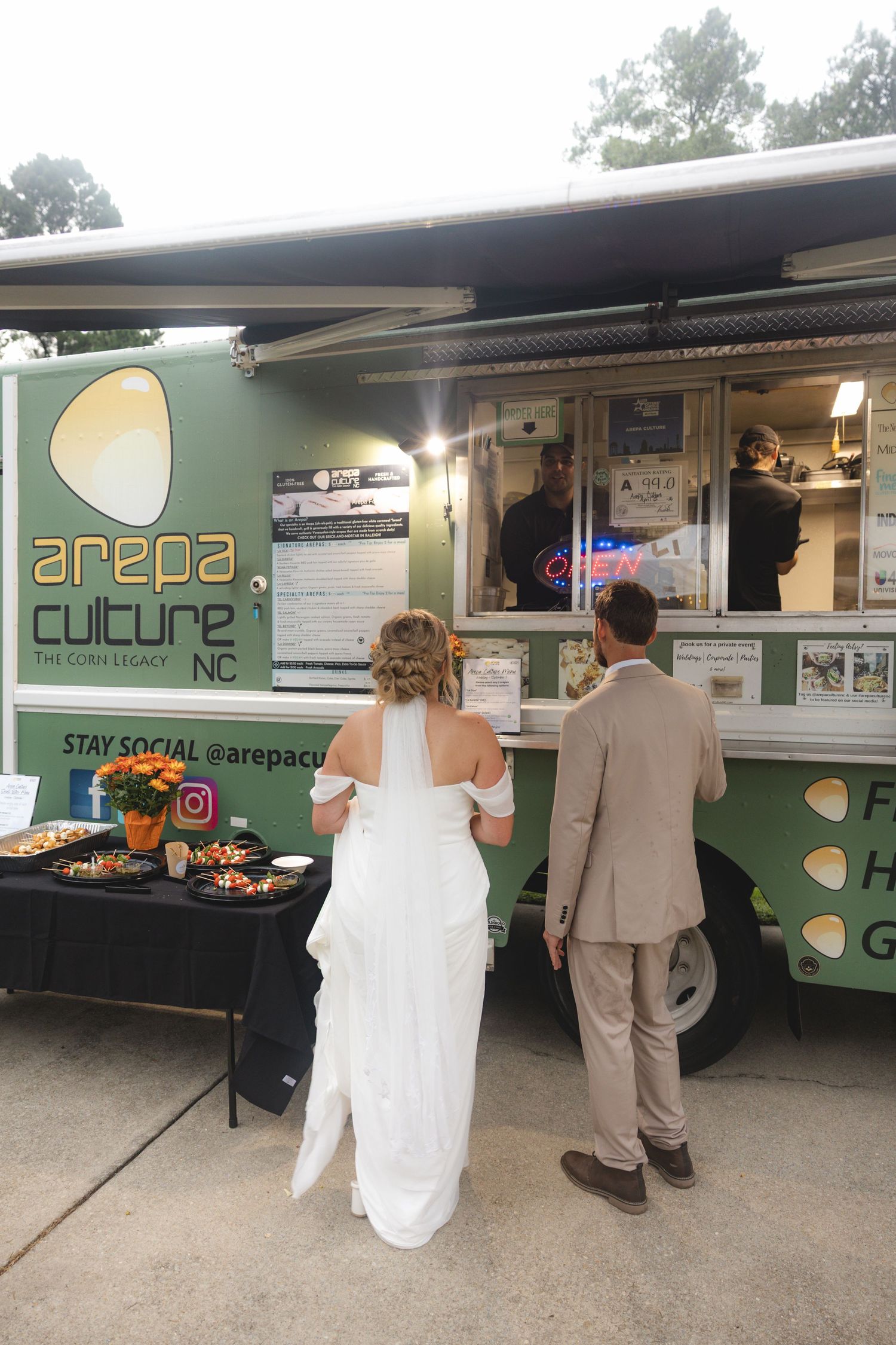 Bride and groom ordering food at Arepa Culture NC food truck at their outdoor wedding reception.