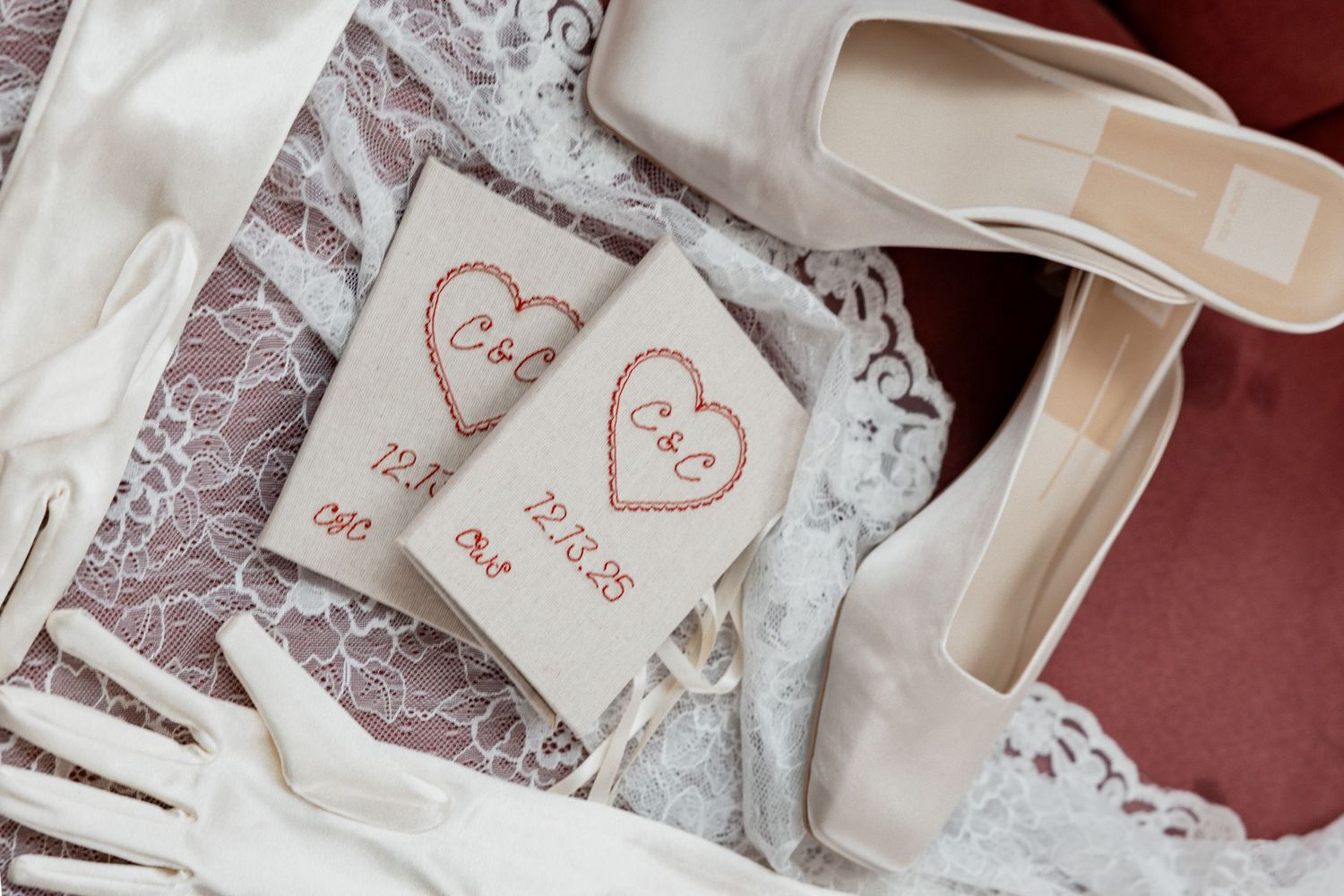 The image shows a pair of handmade embroidered heart-shaped decorations on a lace background.