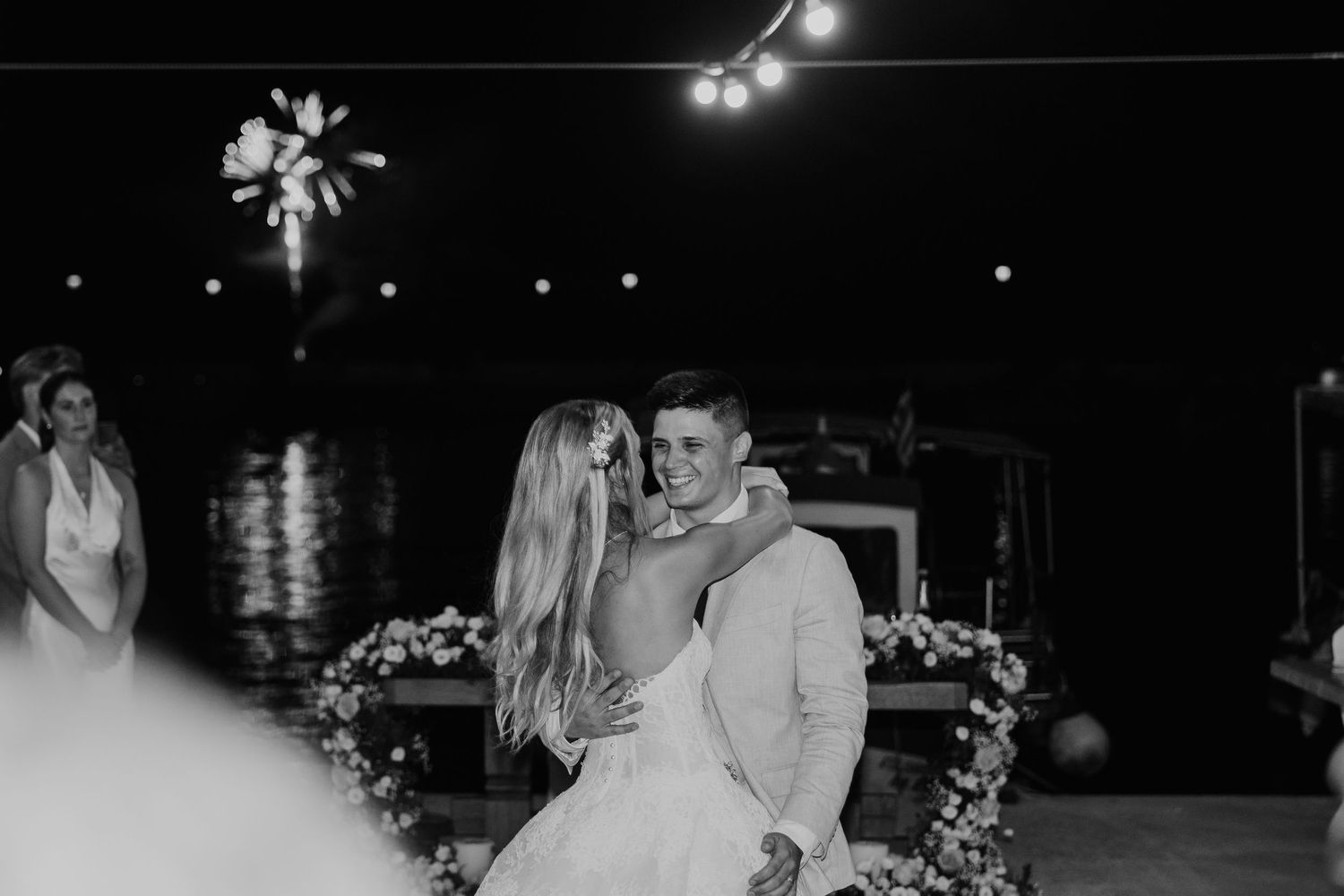 Black and white photo of a bride and groom sharing a romantic first dance at an outdoor waterfront wedding reception.