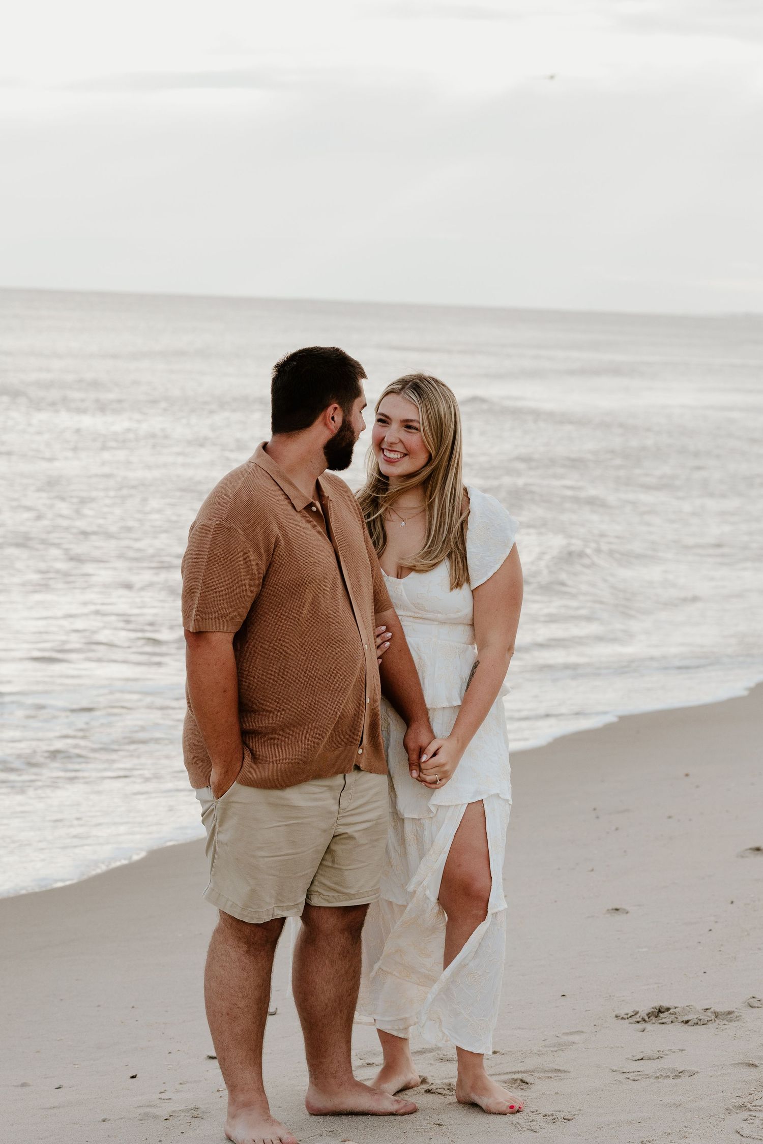 A romantic couple shares an intimate moment on a serene beach at sunset.