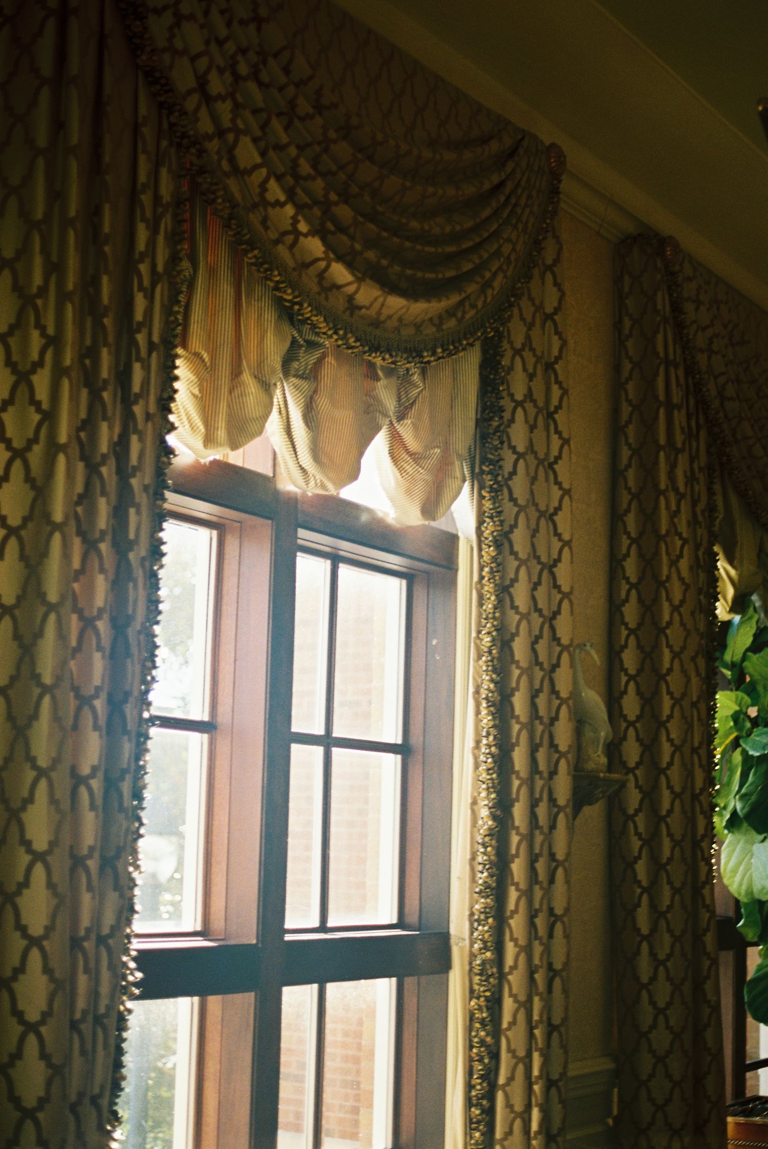 The image shows a window with ornate curtains and decorative drapery, creating a cozy and elegant atmosphere.