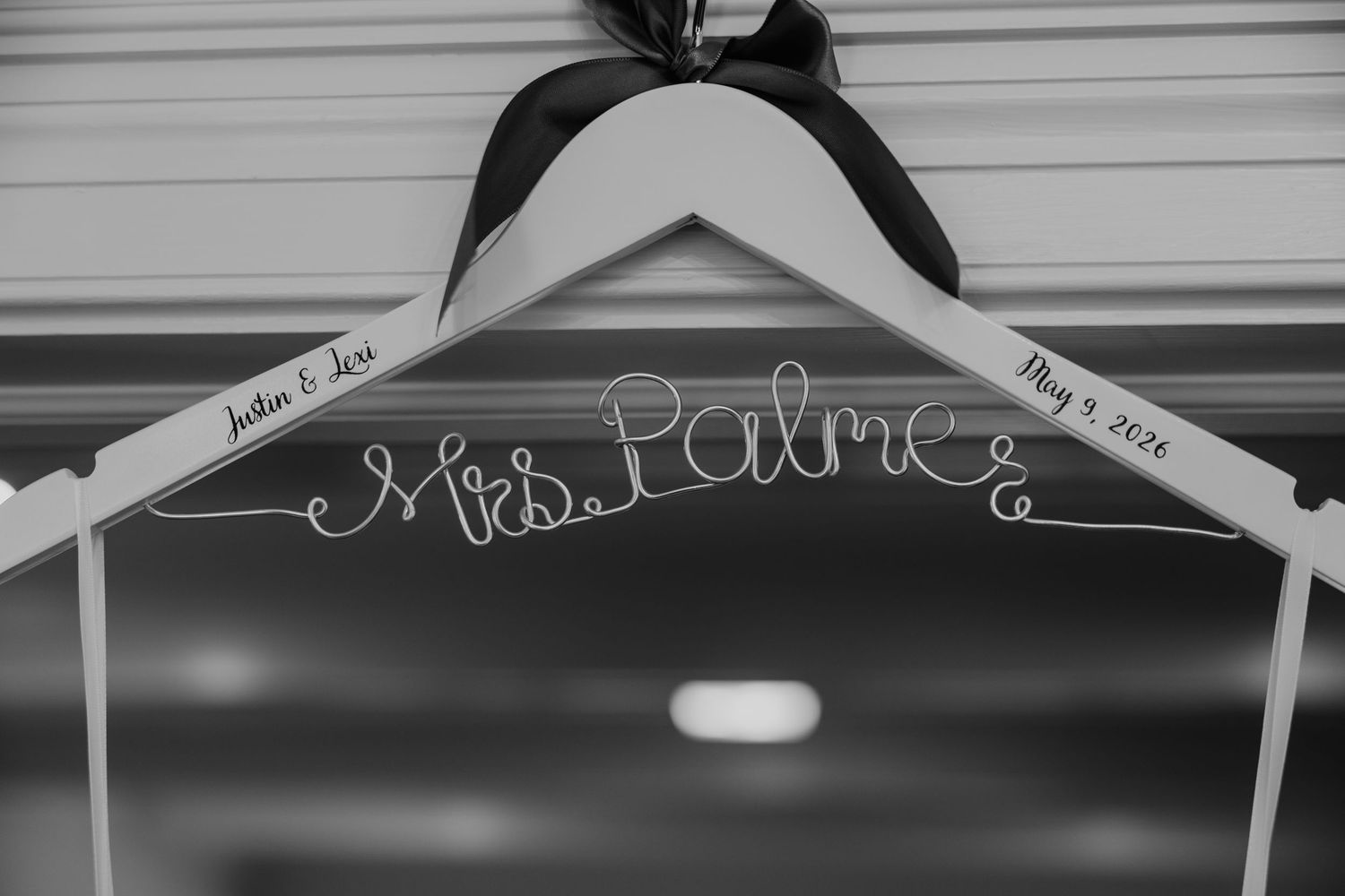 Custom wire wedding hanger reading Mrs. Palme with black ribbon bow and wedding date May 4, 2024.