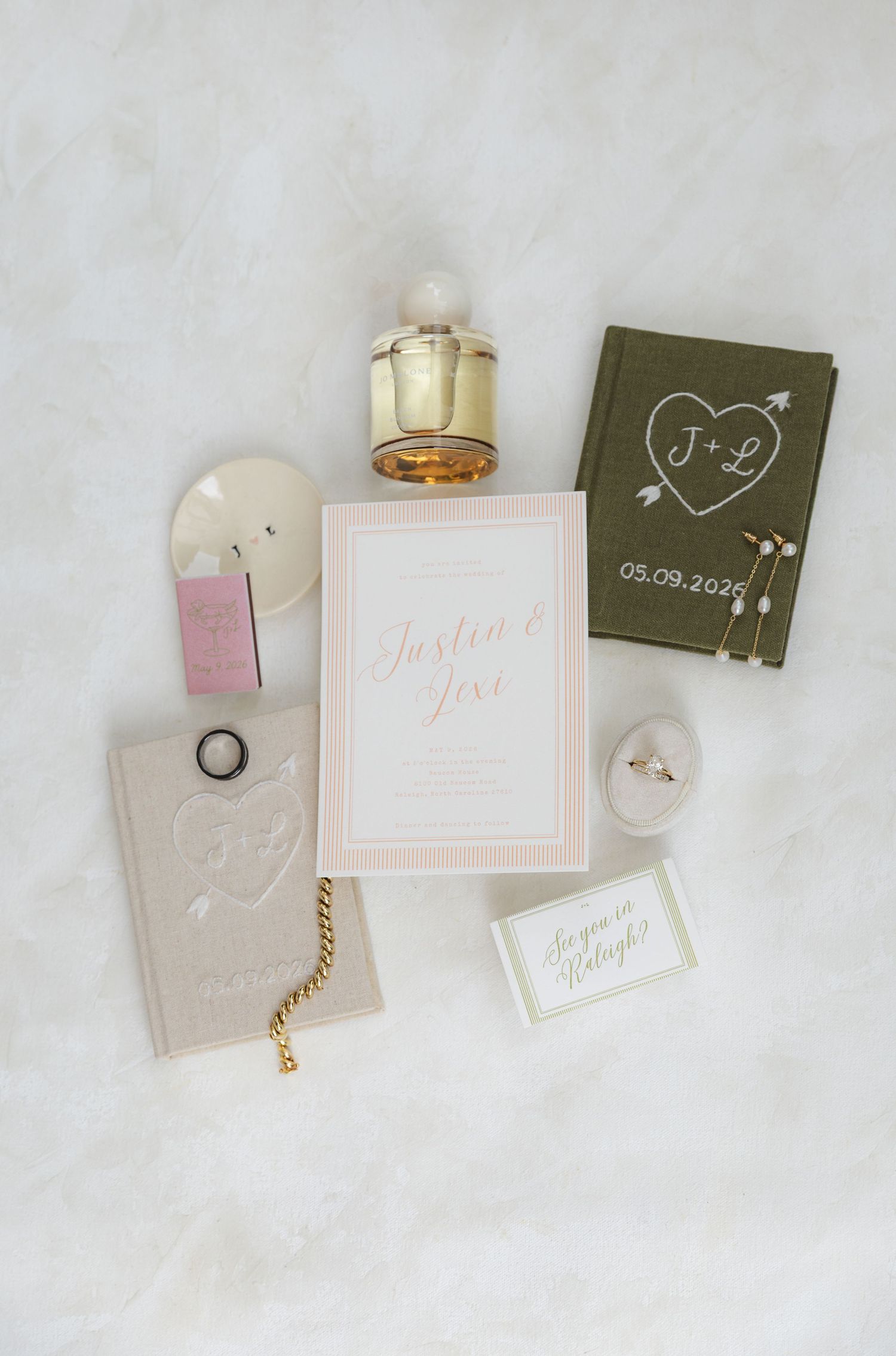 Flat lay of wedding stationery, rings, perfume, and accessories for Justin and Jivi dated 05.09.2026.