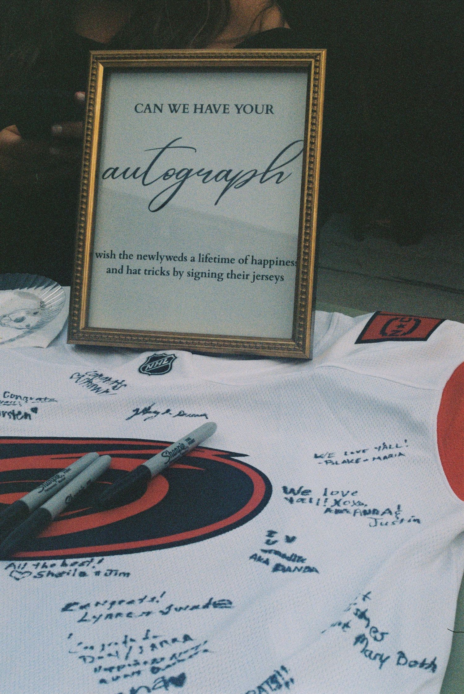 Hockey jersey wedding guest book with autograph sign asking guests to wish newlyweds happiness and hat tricks.