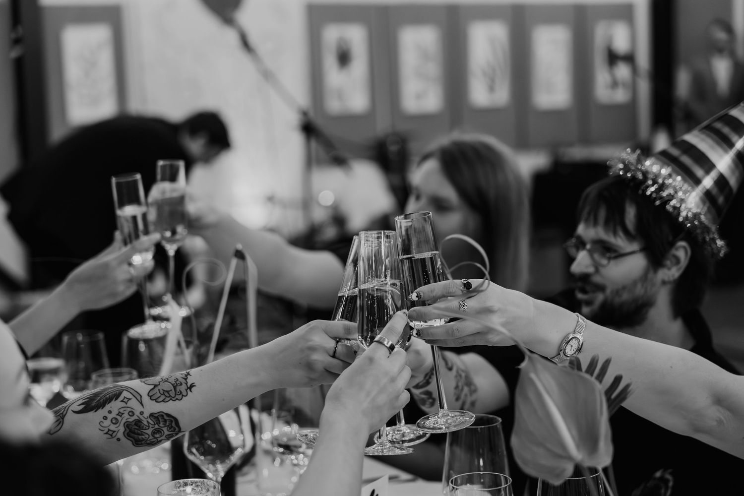 Group of people toasting with champagne glasses at a celebration event in black and white photo.