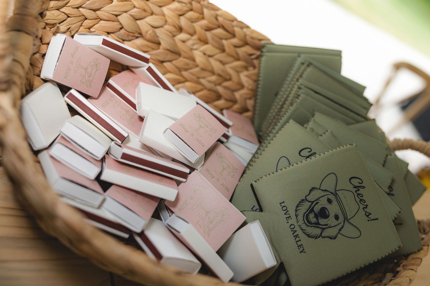 Wicker basket filled with pink and green matchbook wedding favors at outdoor reception.