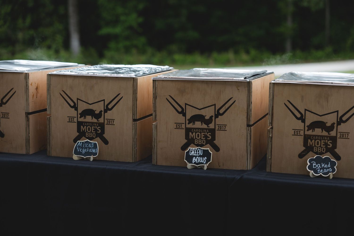 Rows of branded Moes BBQ cardboard food boxes displayed on a table at an outdoor wedding.