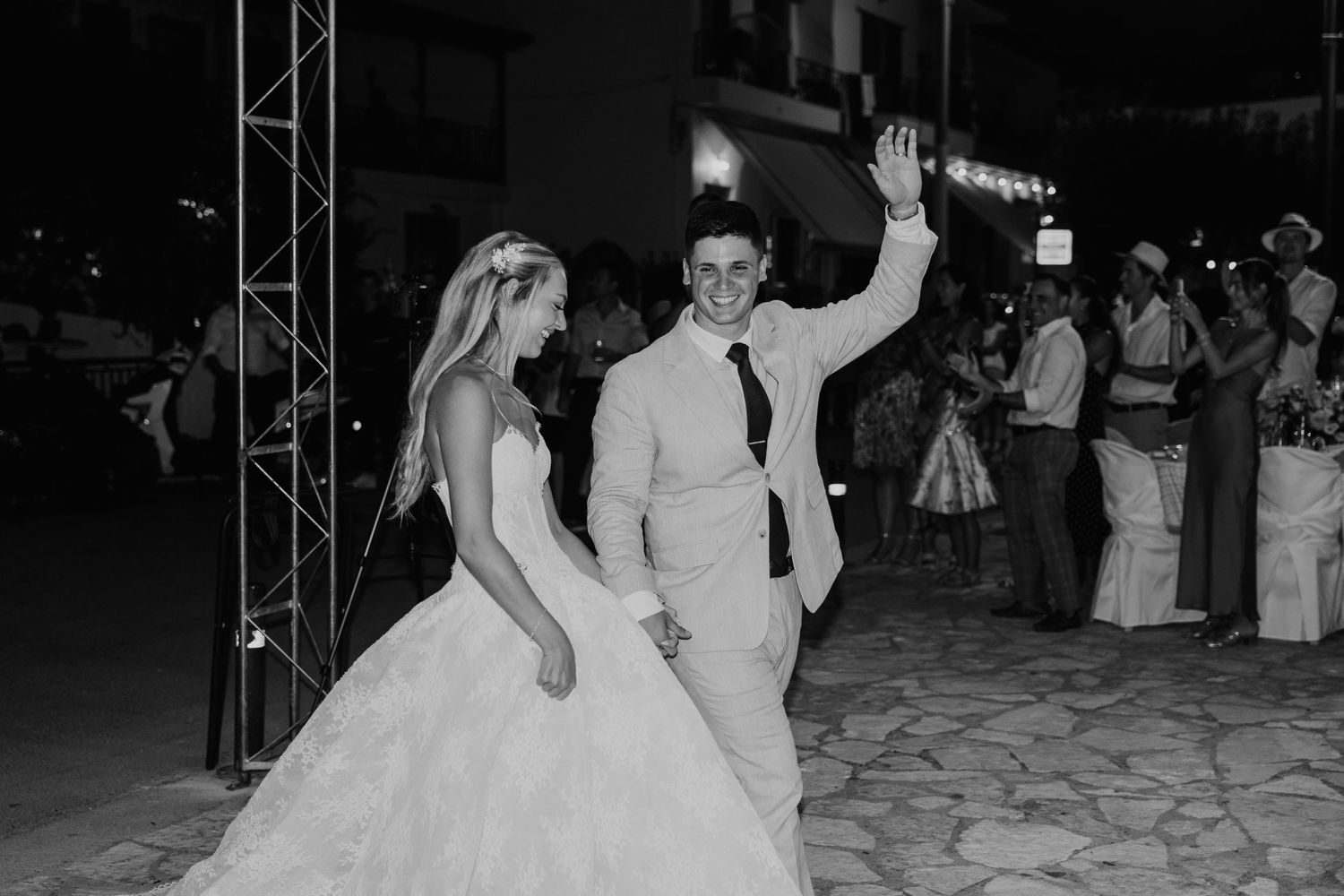 Black and white photo of a bride and groom dancing joyfully at their outdoor wedding reception at night.