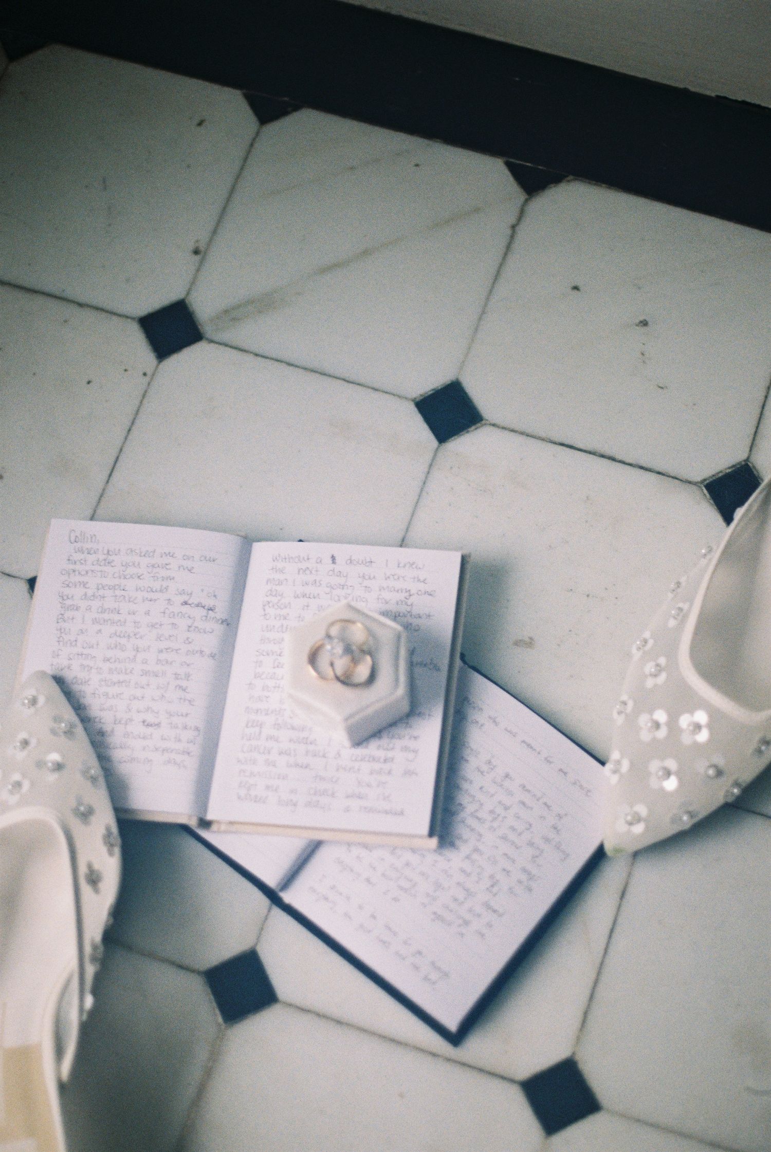 A notebook with handwritten notes and a ring on a tiled floor.