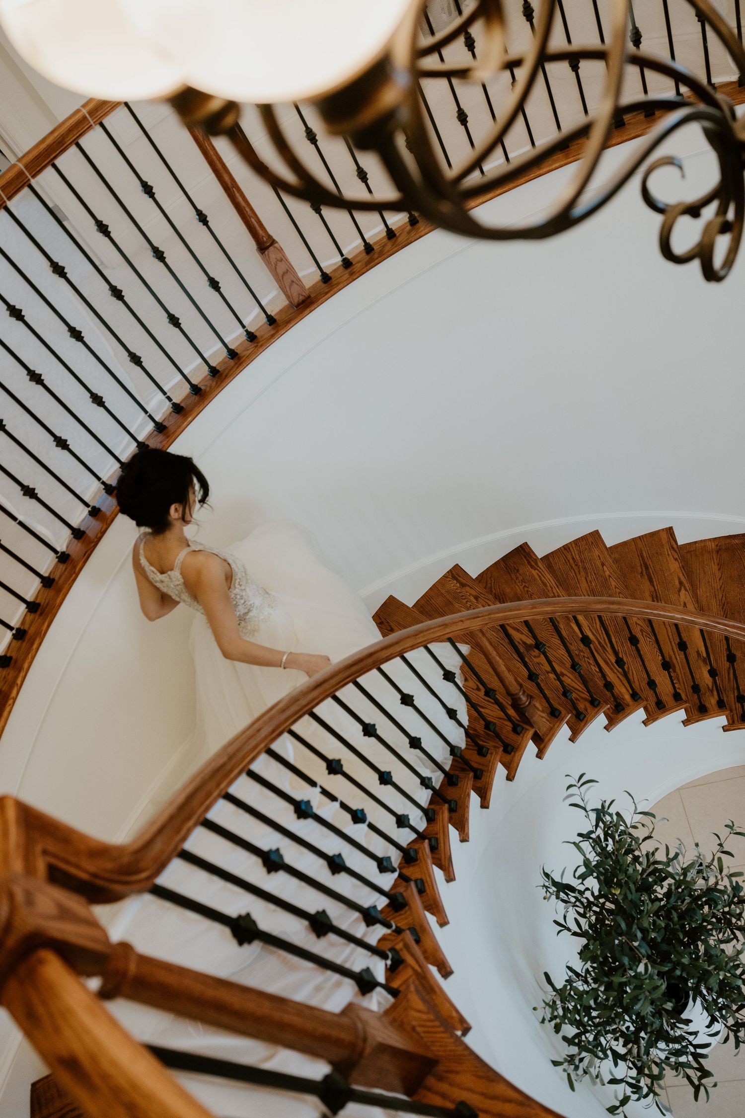 Elegant curved staircase with wooden banister and white walls in wedding venue.