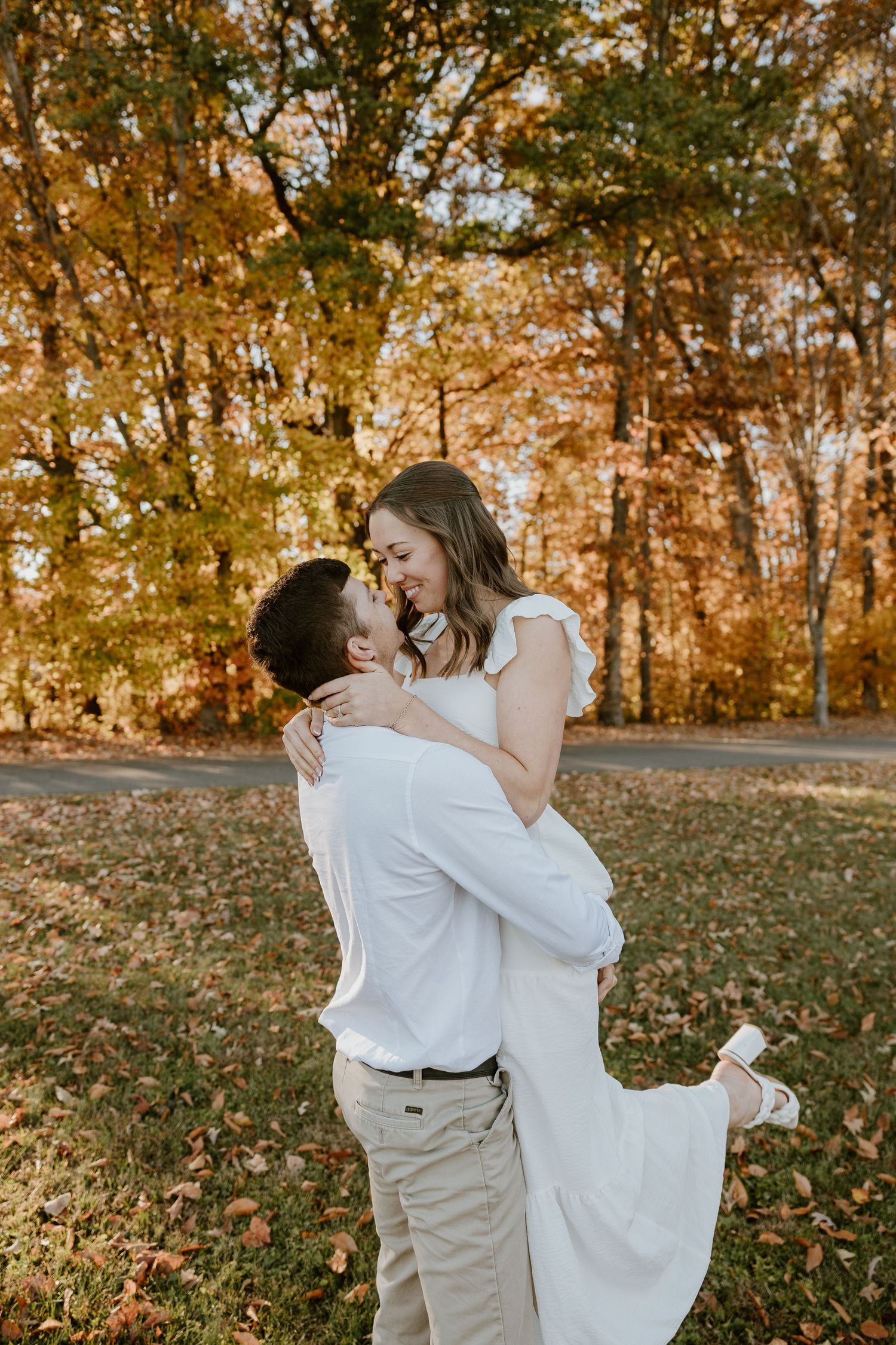 Couple dancing and embracing in a fall setting with golden leaves in the background.