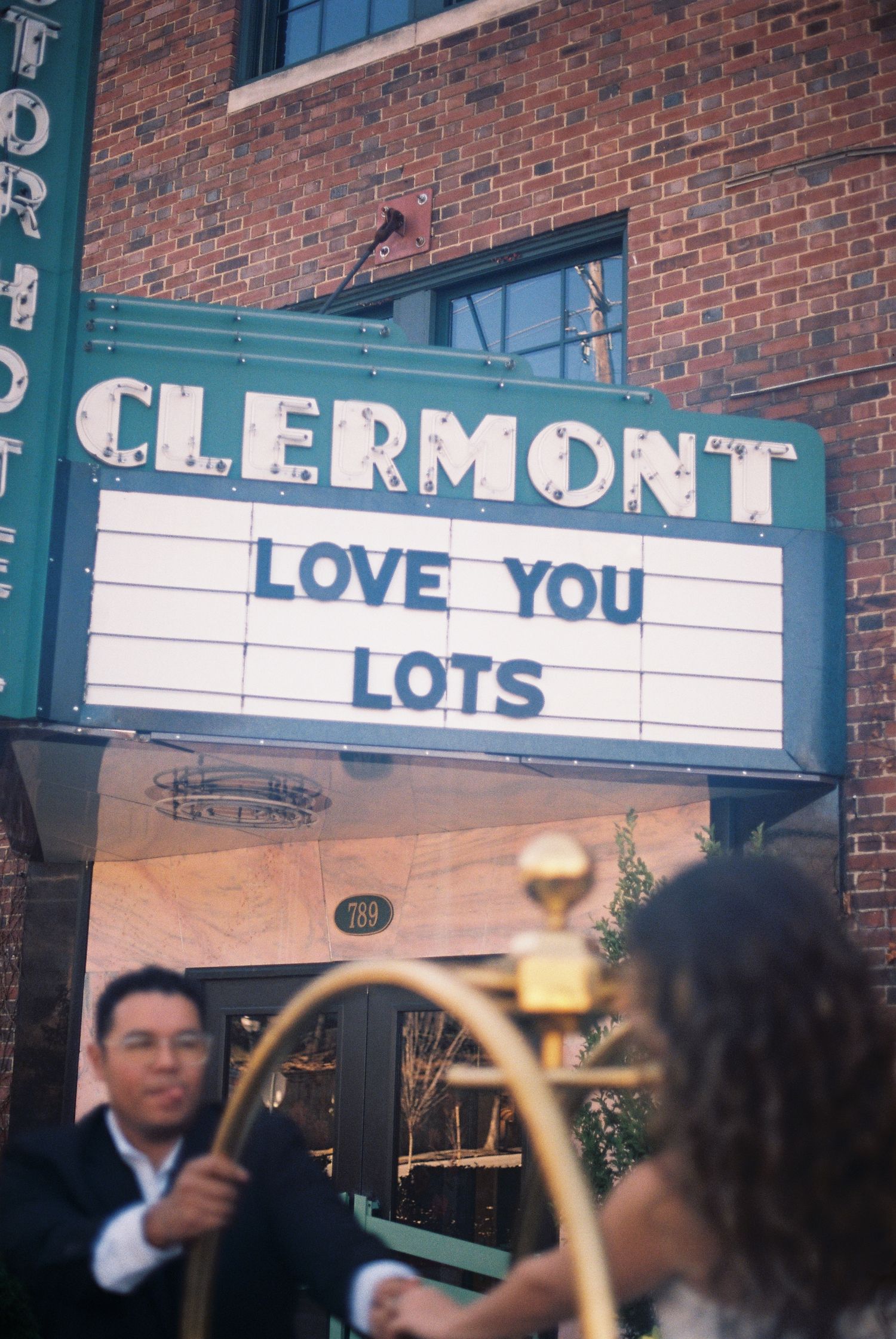 A large neon sign on a brick building that reads 'CLERMONT LOVE YOU LOTS'. Couples engagement session at vintage hotel in Atlanta, Georgia.