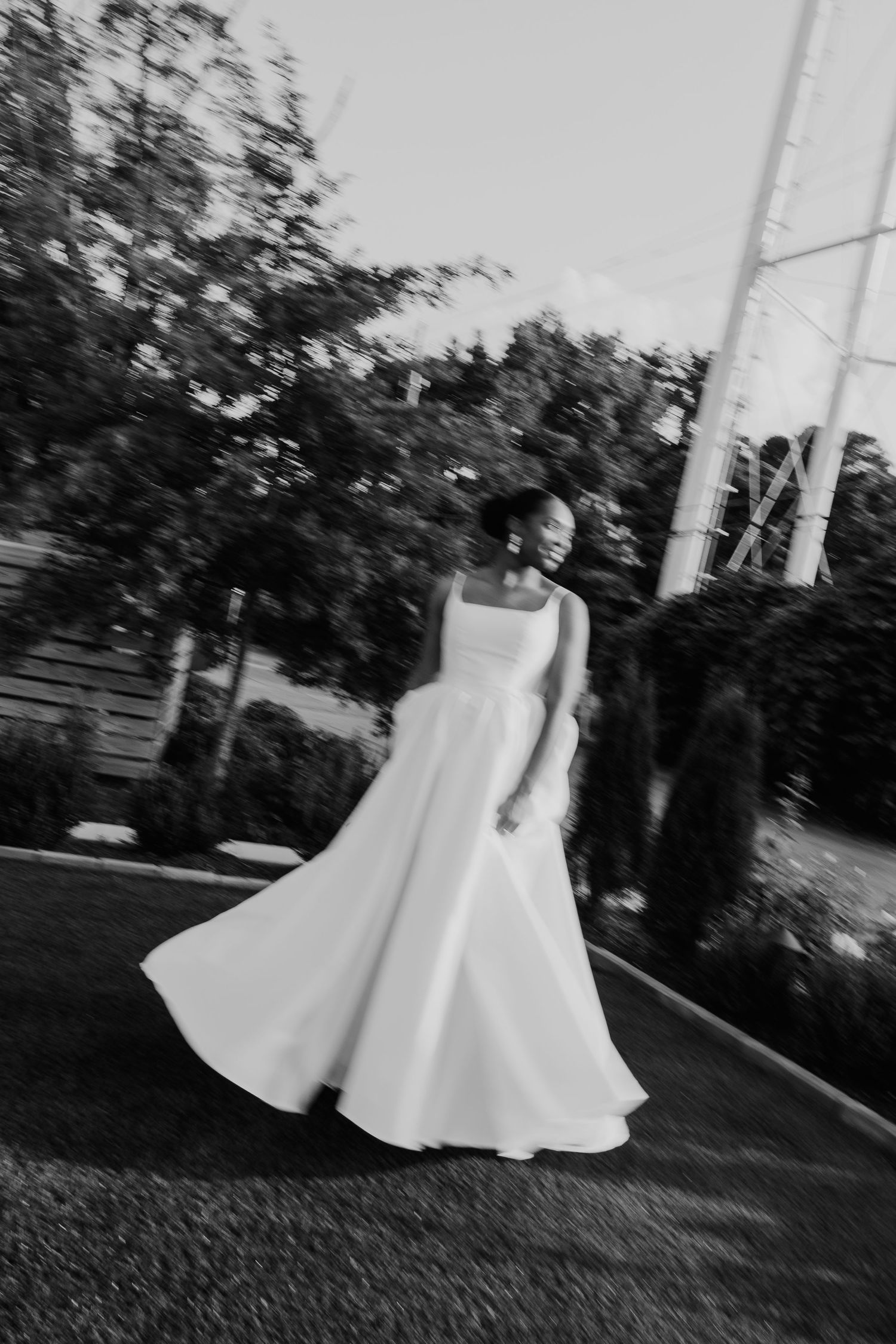 Black and white photo of bride twirling in wedding gown outdoors.