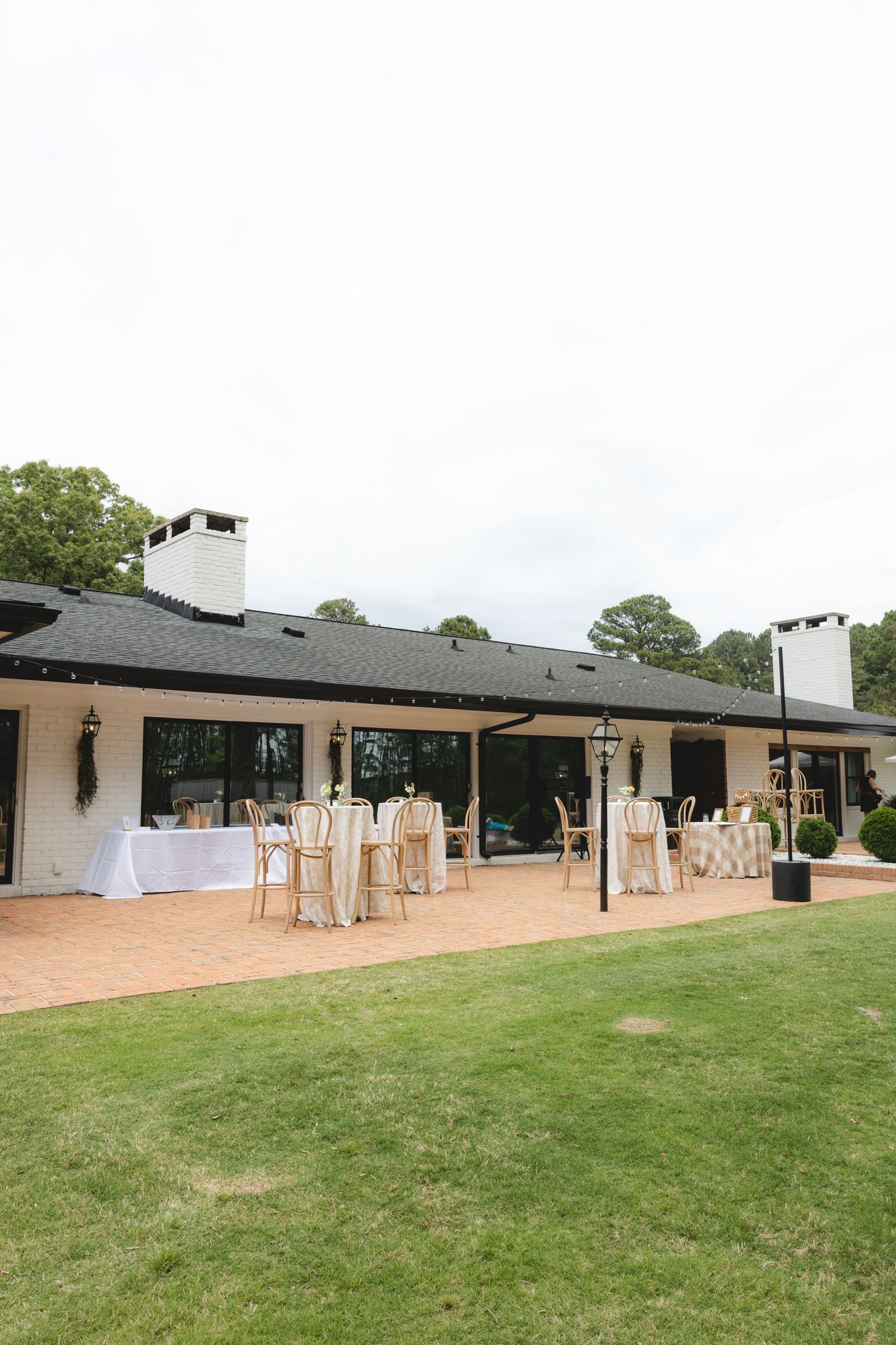 Elegant outdoor wedding venue patio with round tables, chairs, and white tablecloths on sunny day.