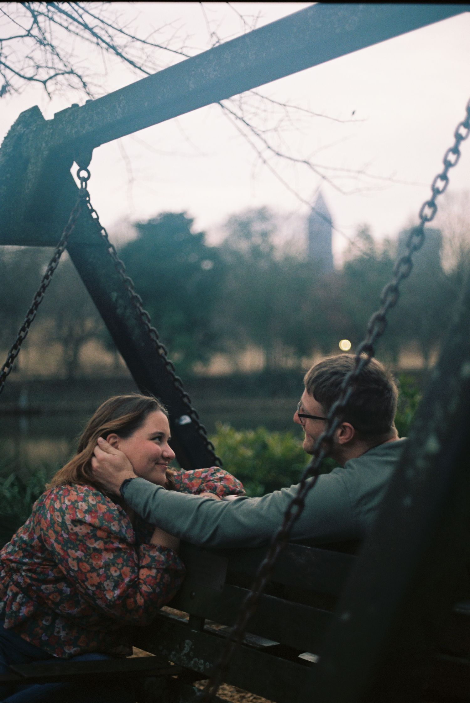 People swinging together on playground swings at dusk with a dreamy atmospheric feel.