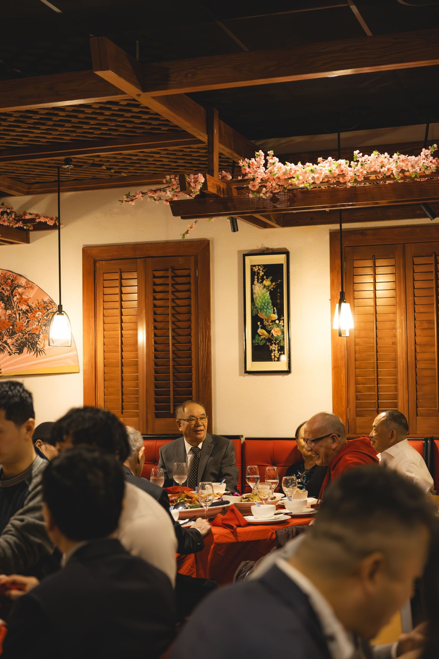 Guests dining at warmly lit Asian restaurant with floral ceiling decor.