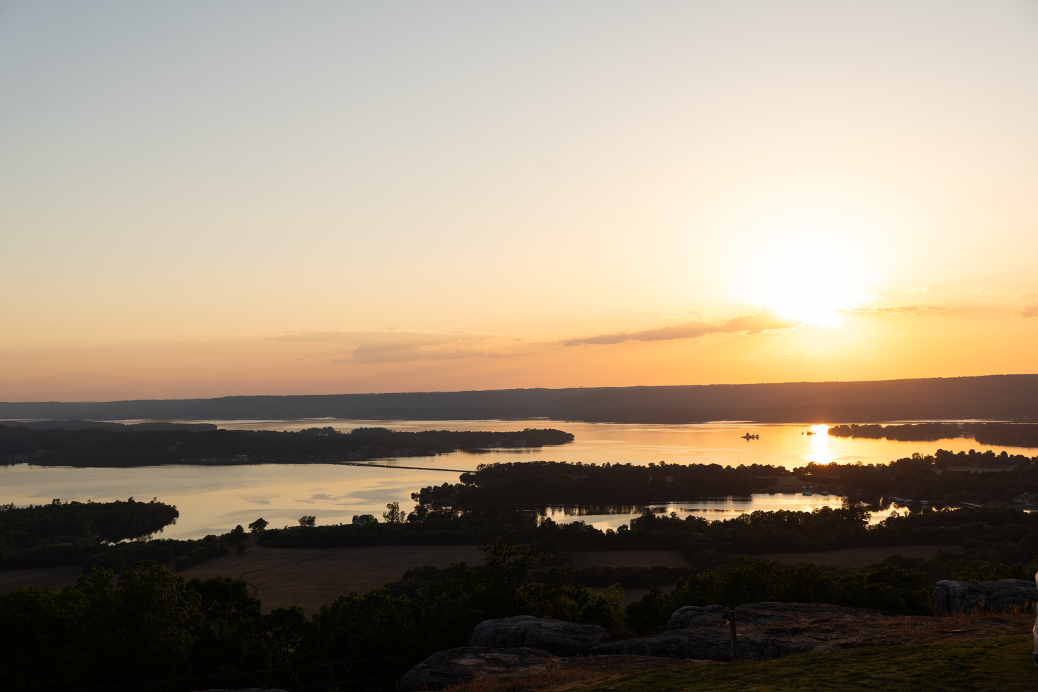 Aerial view of a stunning sunset over a vast river landscape with golden reflections on calm waters.