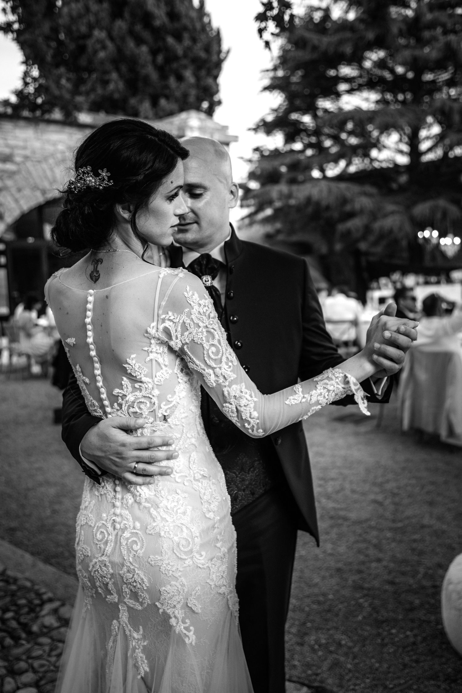 Black and white romantic photo of bride and groom sharing a dance at an outdoor wedding venue.