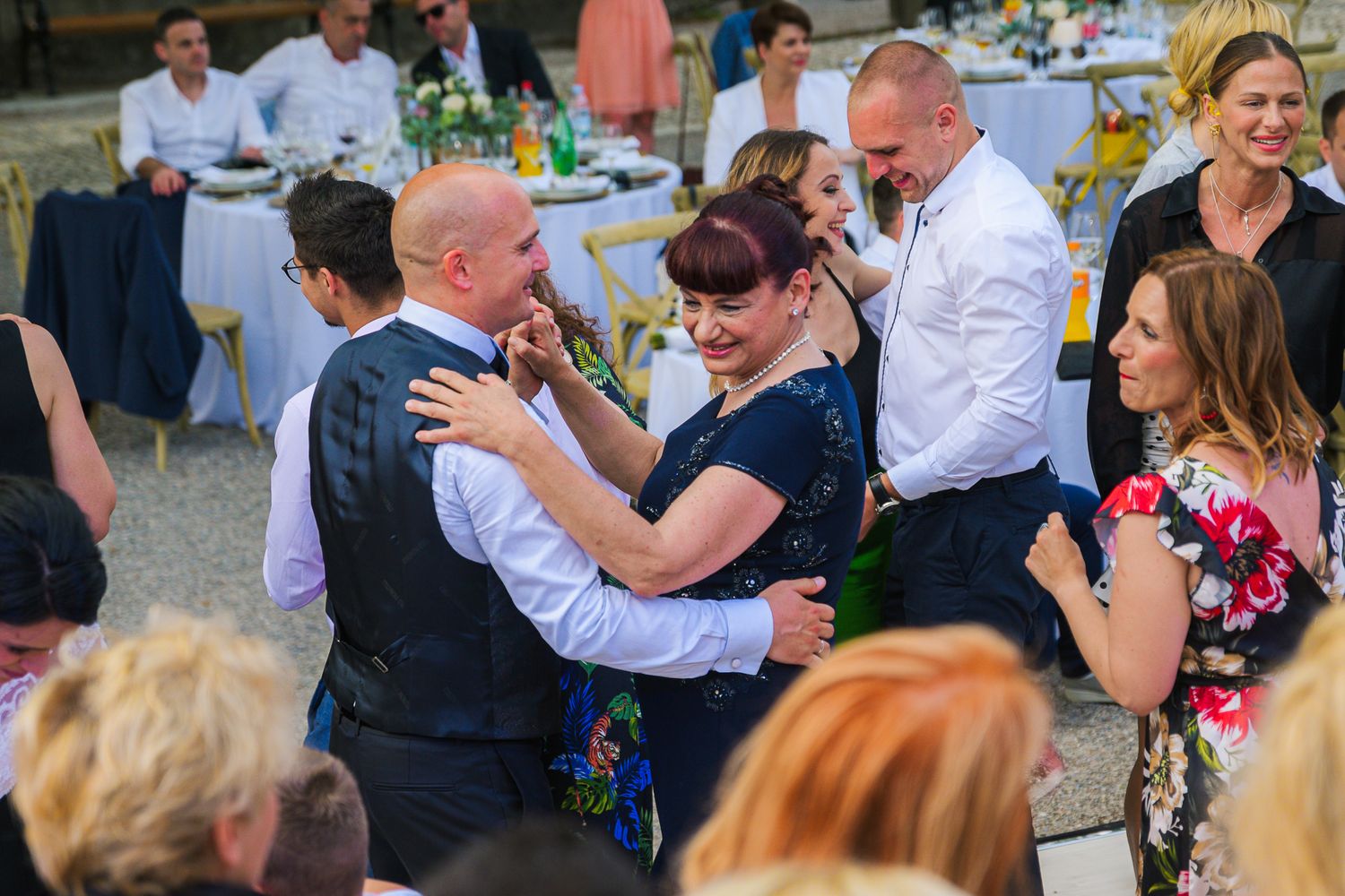 Wedding guests sharing warm embraces and dancing together at an elegant outdoor reception.