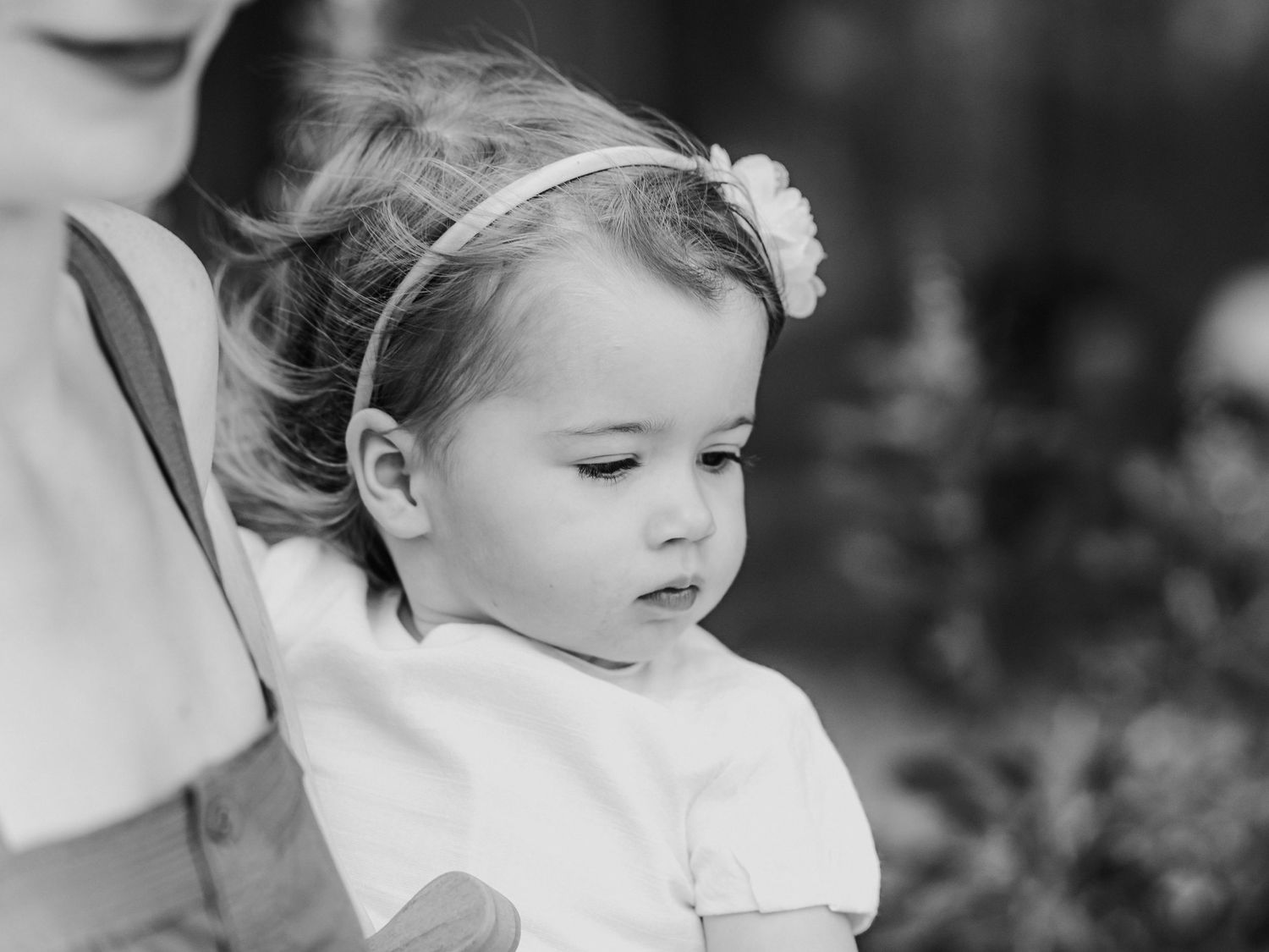 Black and white portrait of cute toddler girl in white dress with floral headband.