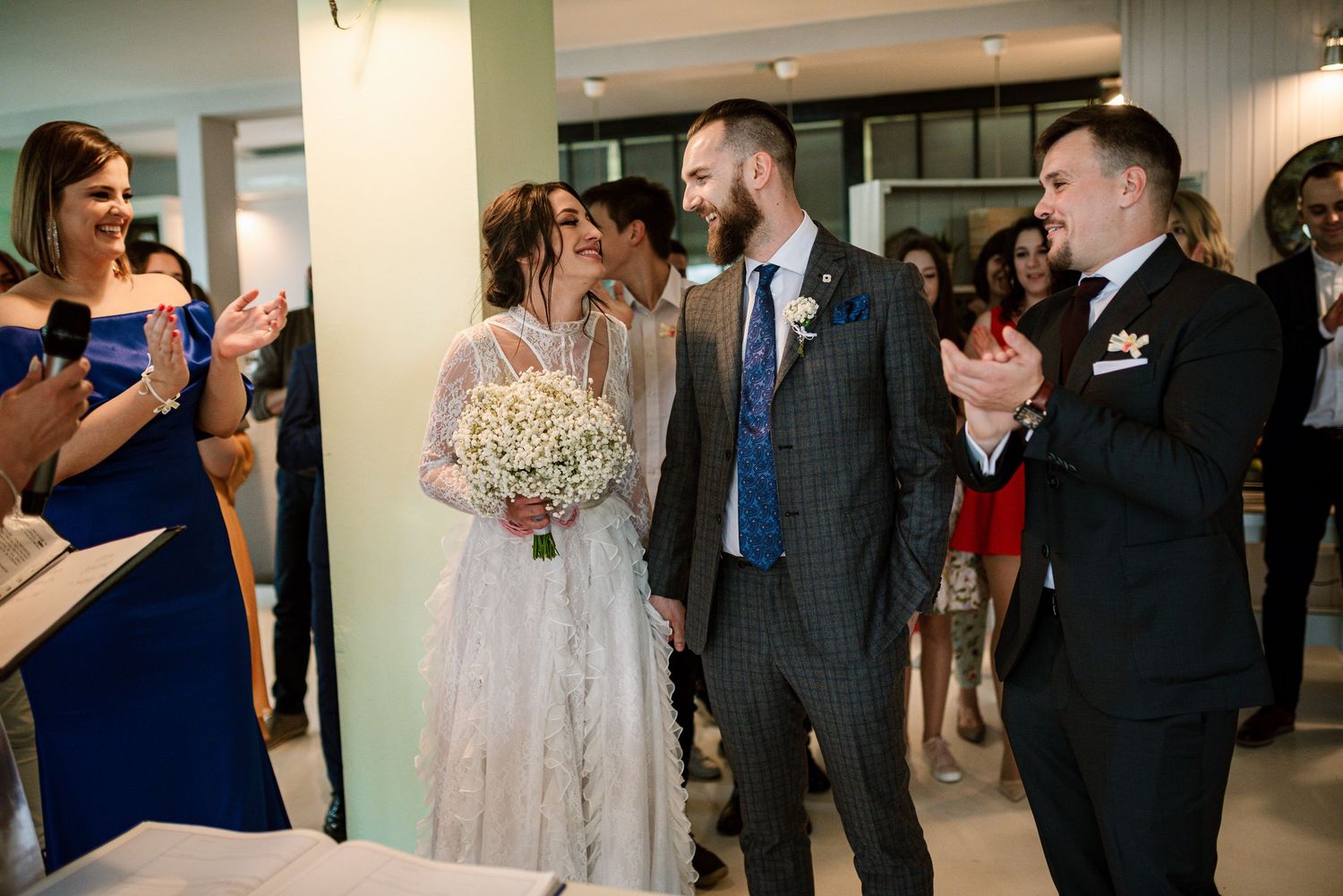 Newlyweds walk hand in hand while guests applaud during wedding reception celebration.