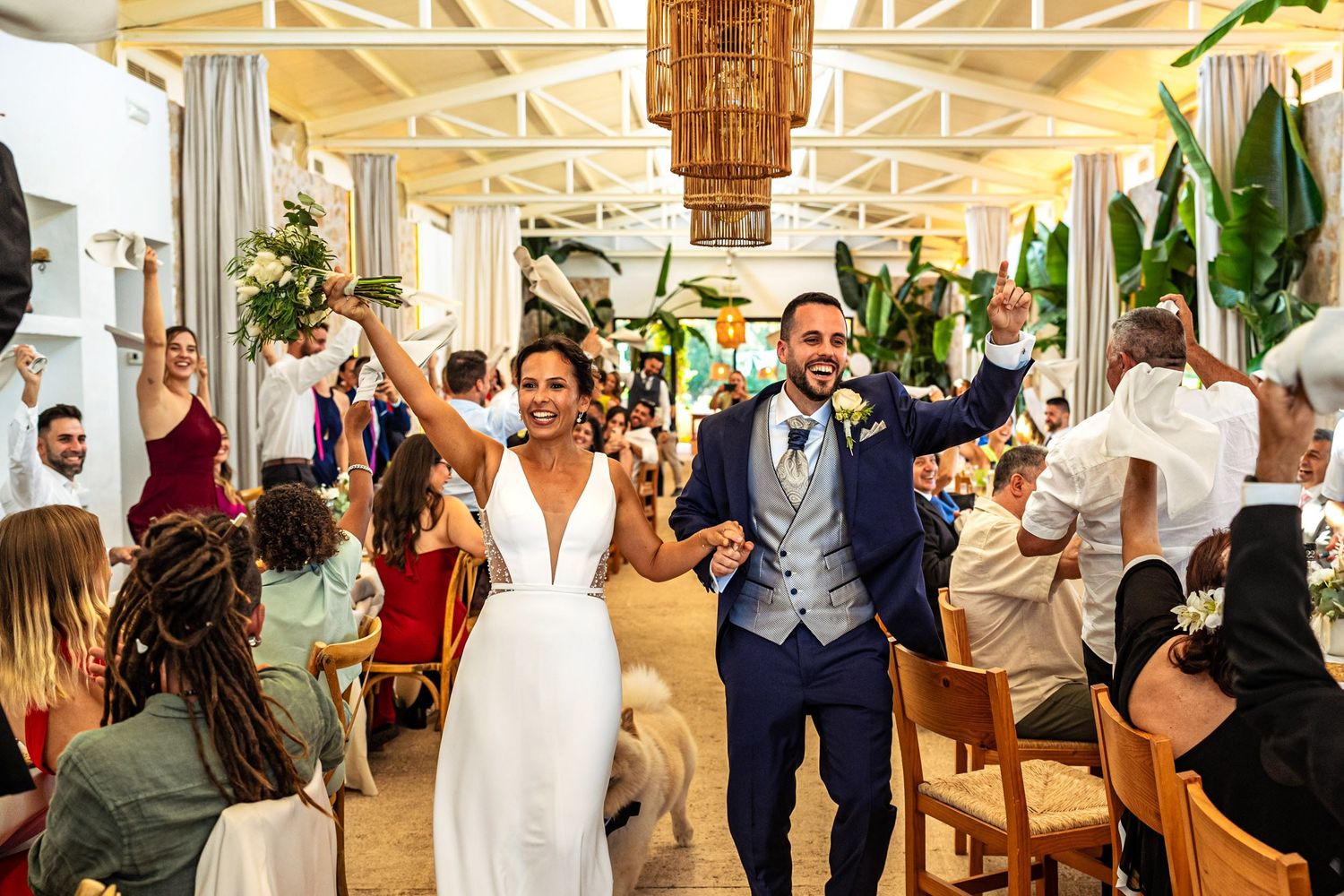 Bride and groom celebrating their wedding reception, holding hands and smiling as guests cheer around them. Herzenshaus Studio, Frankfurt.