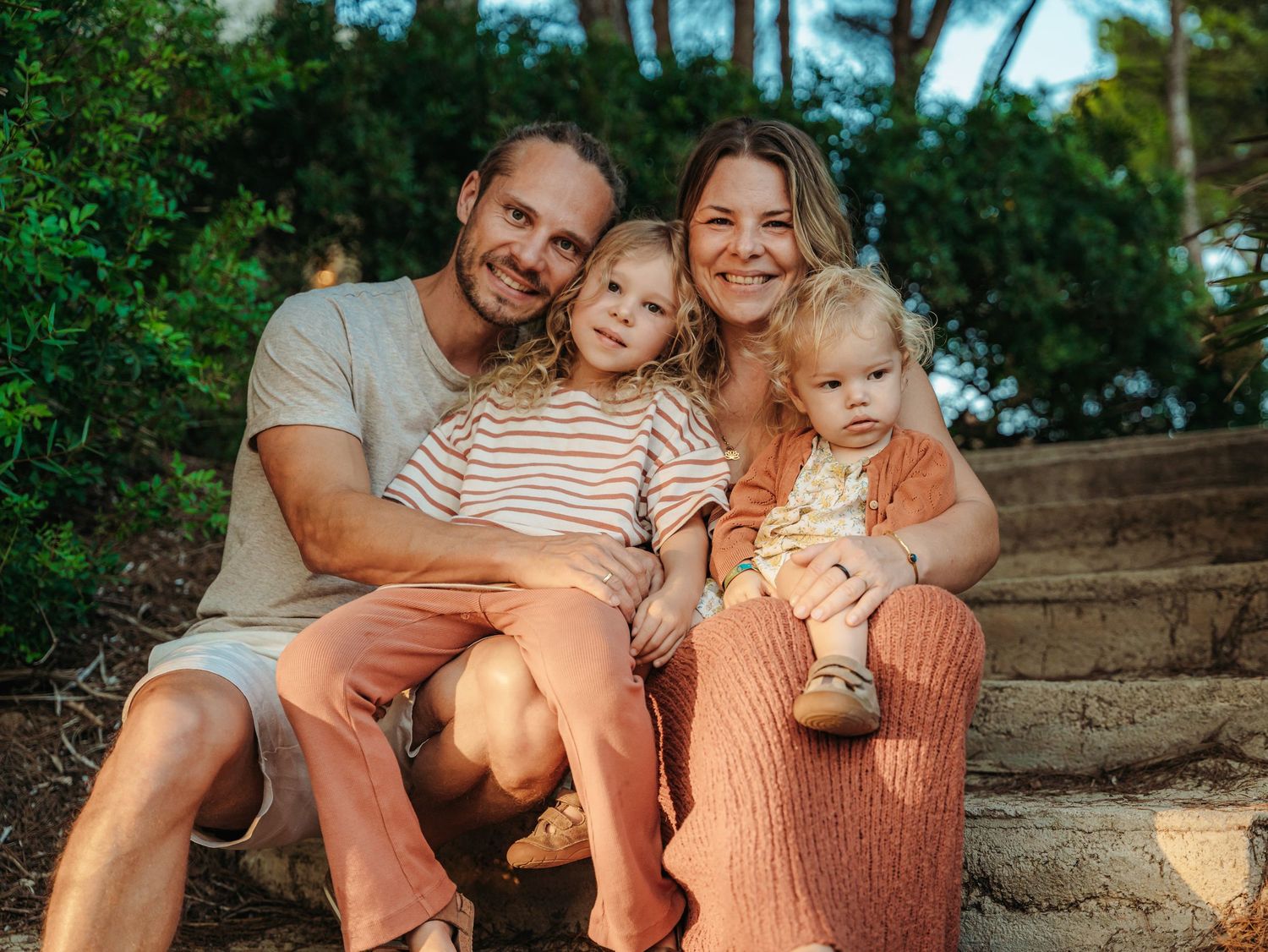 Family of four sharing a relaxed outdoor portrait surrounded by nature, capturing warm connection during family photography session.